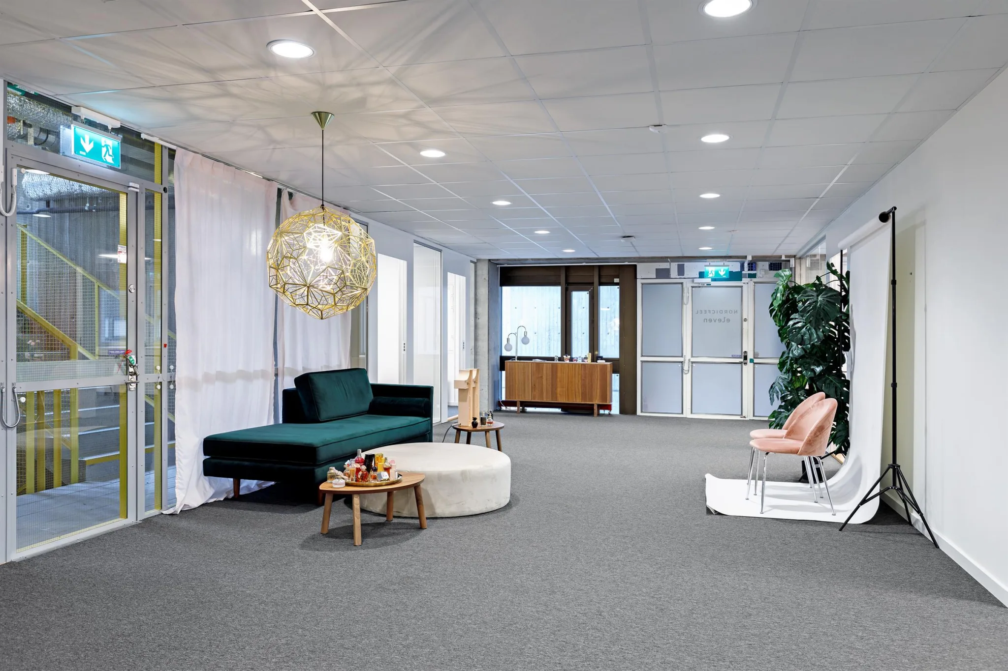 4. Ett loungeområde med en grön soffa, bord och dekorativa lampor samt växter i hörnet.