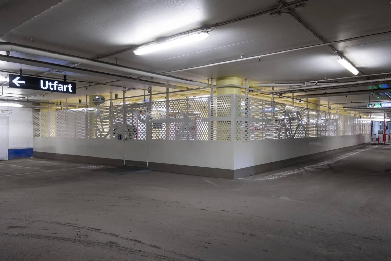 3. Ett parkeringsgarage med ett inhägnat område fyllt med teknisk utrustning, belyst av lysrörslampor.