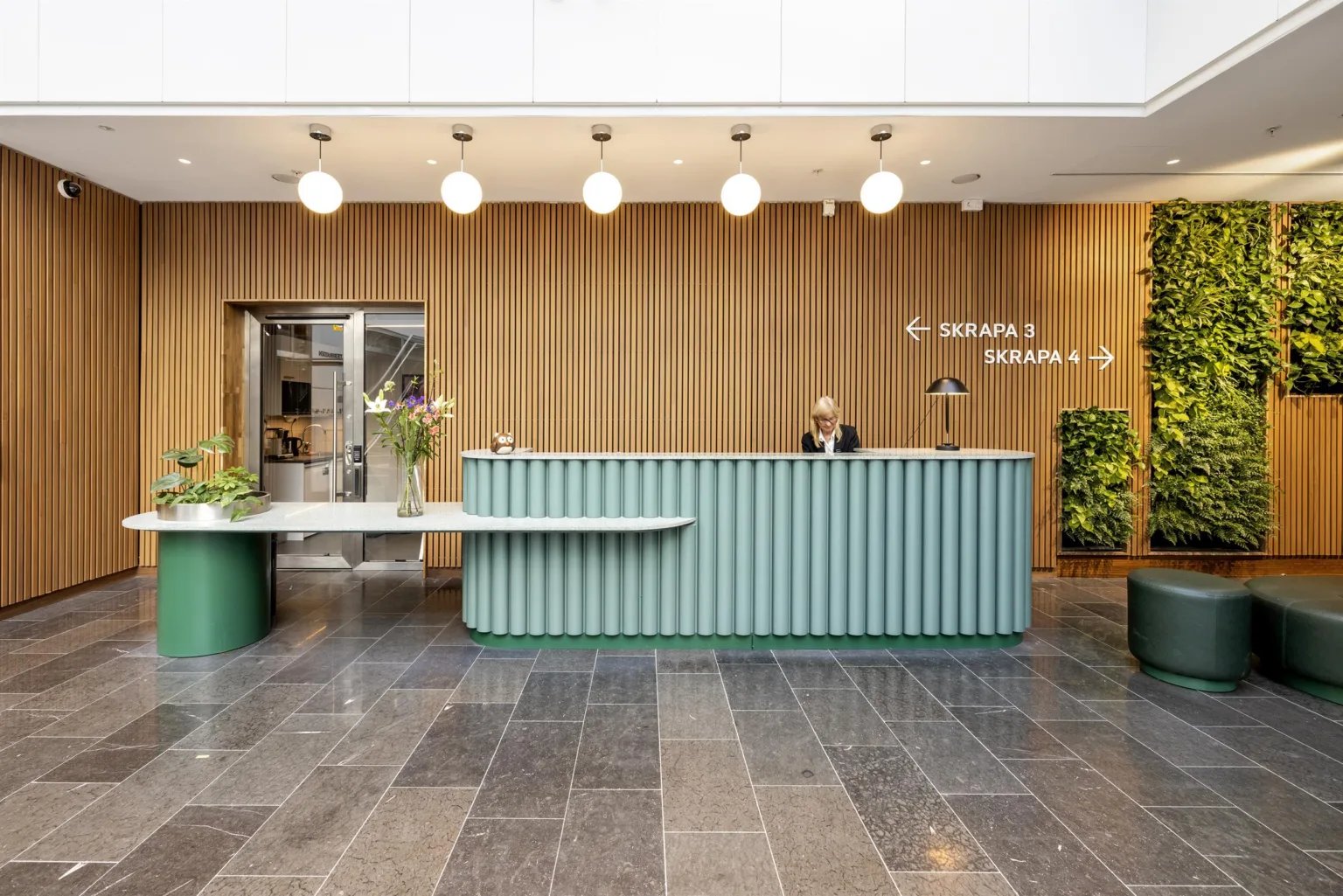 3. En reception med en ljusblå disk, en vägg av träpaneler i bakgrunden och skyltar som visar riktningar.