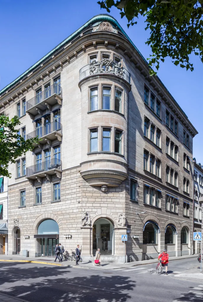 En historisk byggnad med ljus stenfasad och detaljerade fönster samt ett valv vid entrén.