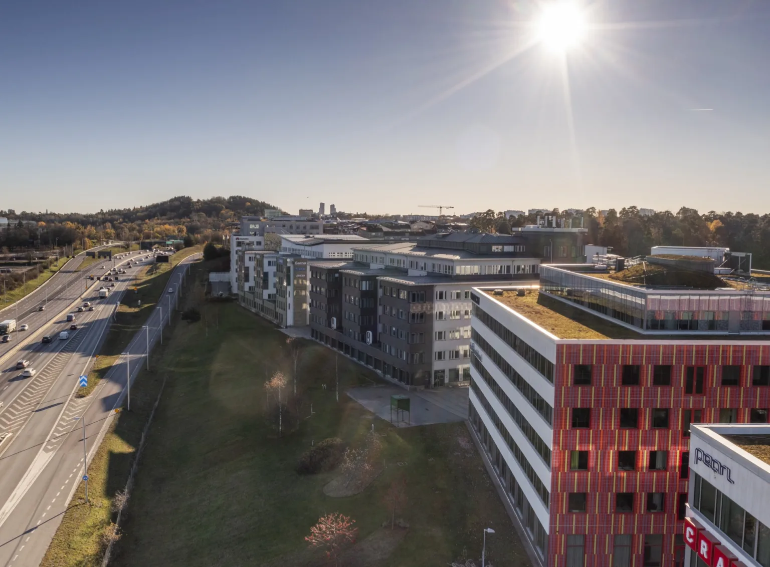 En vy över ett område med moderna byggnader, grönområden och solig himmel.