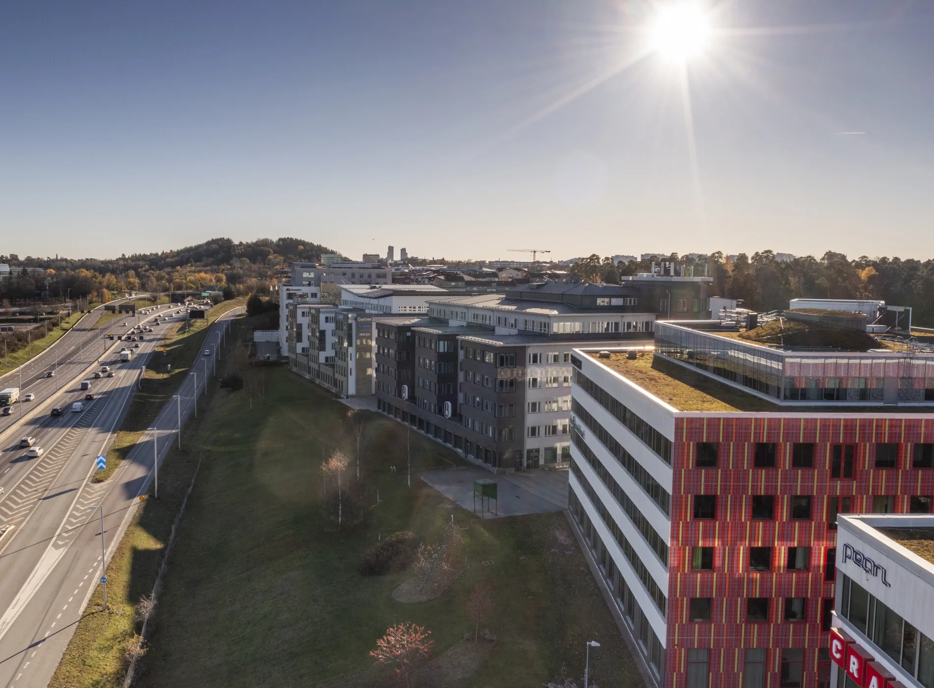 En vy över ett område med moderna byggnader, grönområden och solig himmel.
