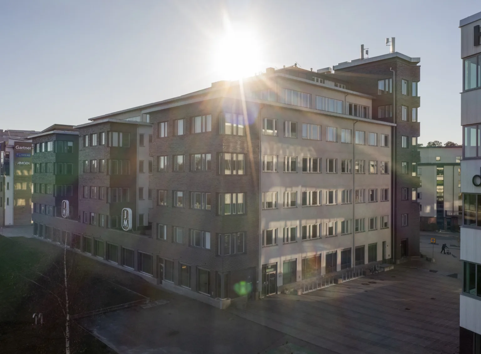 En byggnad med glas- och betongfasad, där solen strålar över taket och skapar ett starkt ljusflöde.