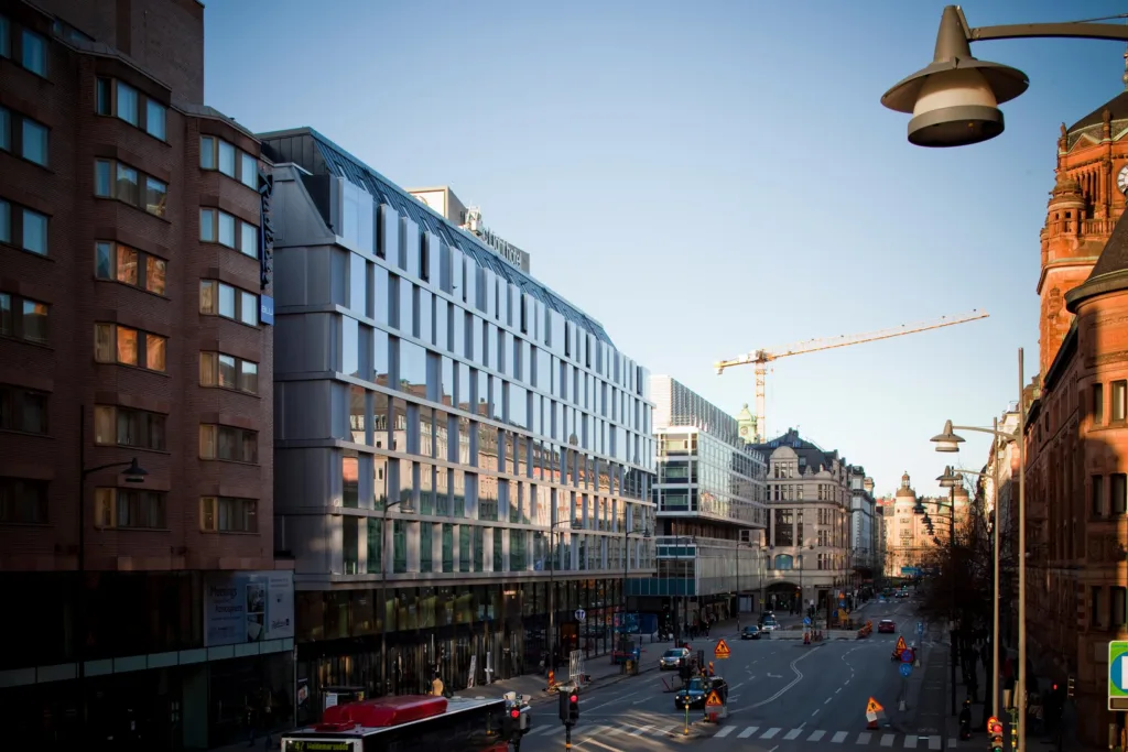 4. En stadsvy med moderna byggnader längs en bred gata, byggnadsarbete pågår och en byggkran syns.