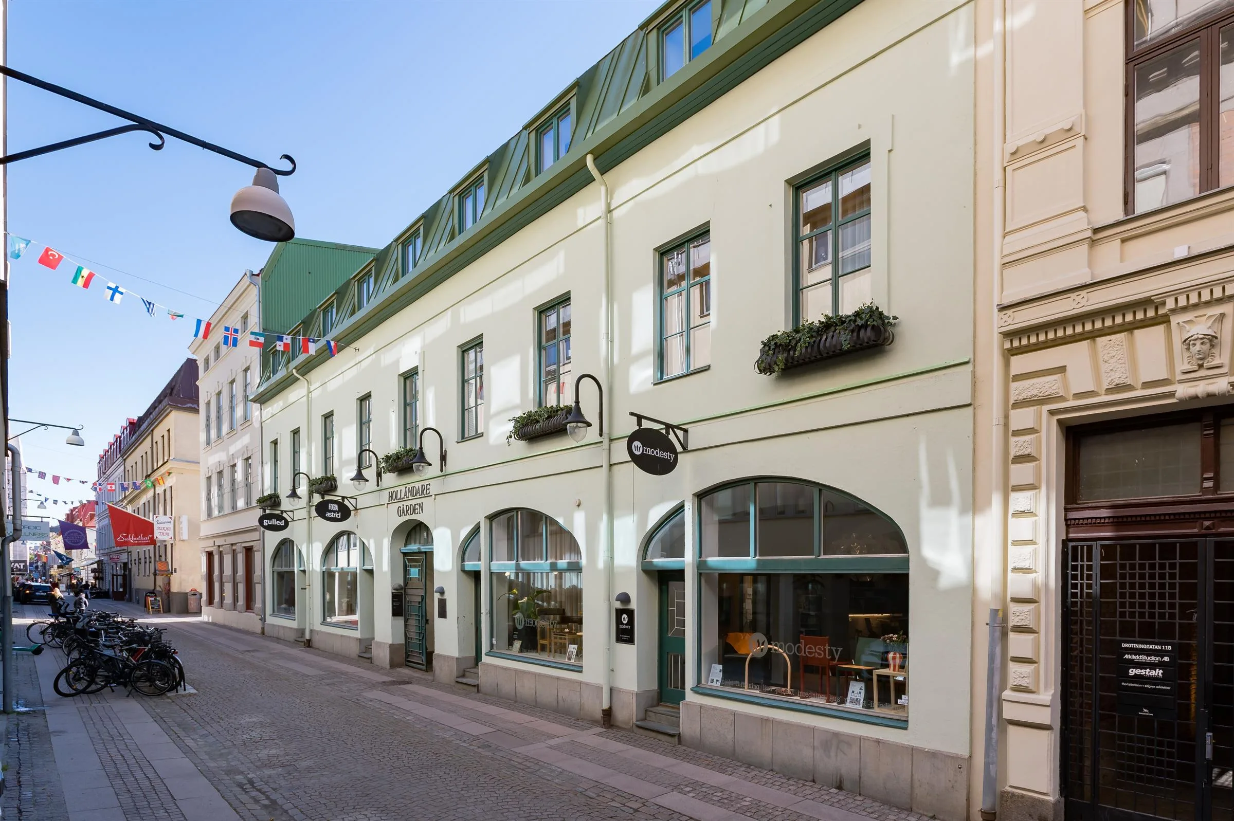 Gata med en ljus fasad och stora fönster, samt en skylt med en butik eller restaurang.