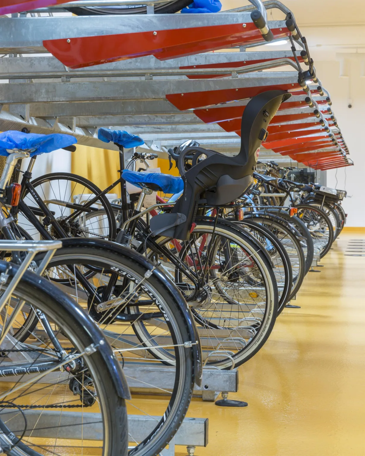 En rad parkerade cyklar i en cykelställning inomhus med färgglada detaljer.