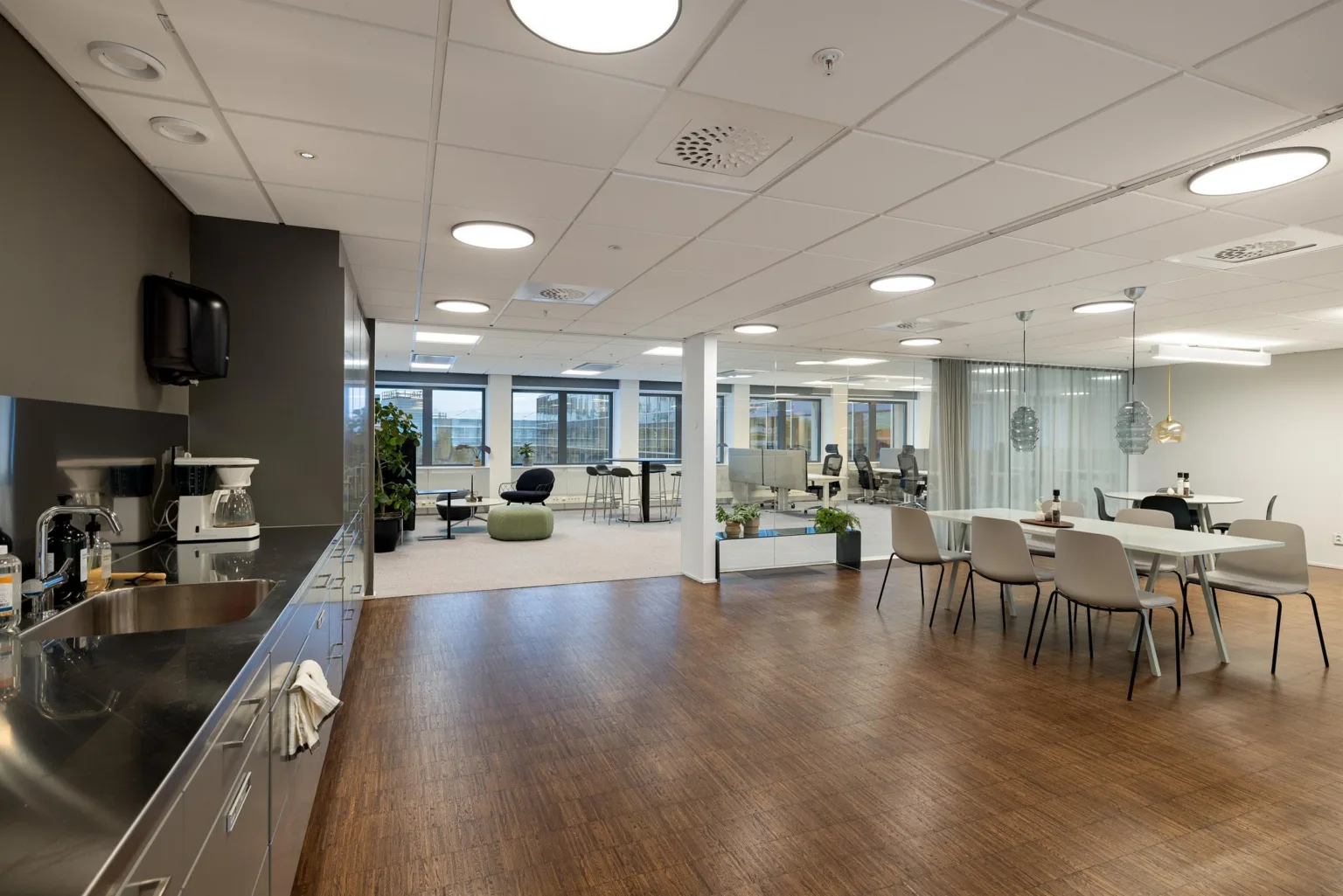 Ett öppet kontorsutrymme med köksdel, matbord och sittmöbler.