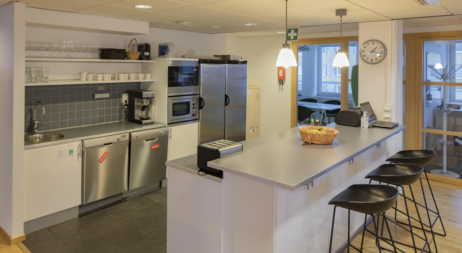 2. Ett ljust kök med moderna vitvaror, en bardisk och hängande lampor.