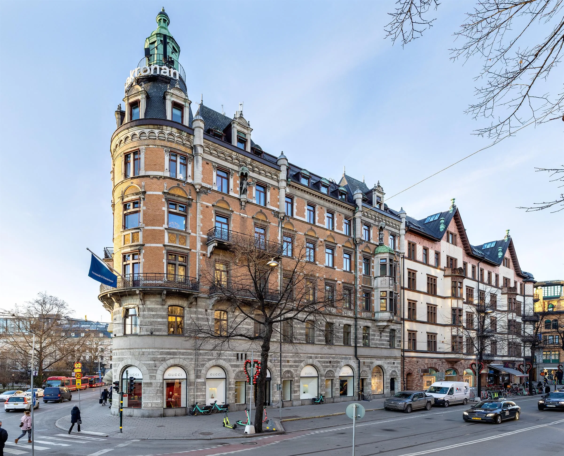 En hörnbyggnad med orange fasad och ett torn, prydd med flaggor och omgiven av stadsgata.