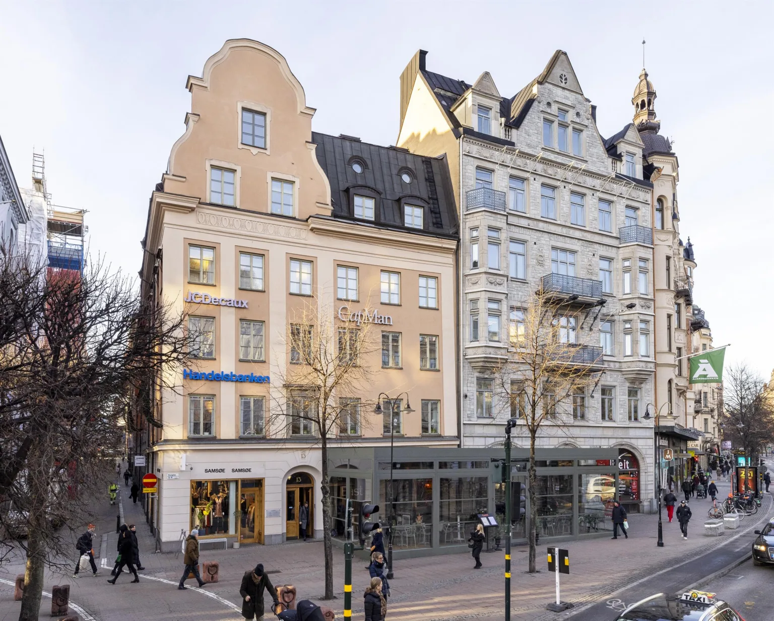 3. Hörnet av en gata med historiska byggnader, människor och glasfasader.