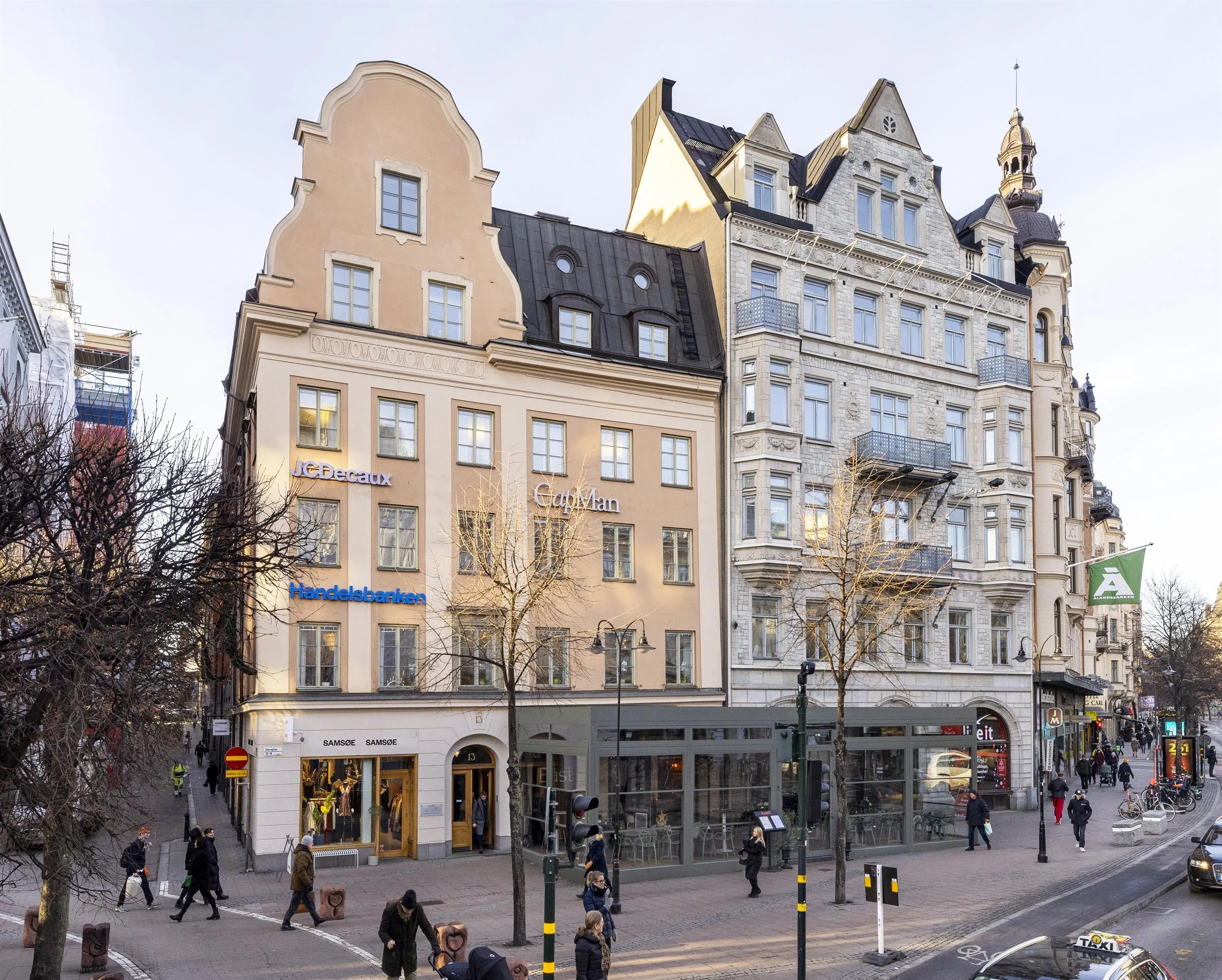3. Hörnet av en gata med historiska byggnader, människor och glasfasader.