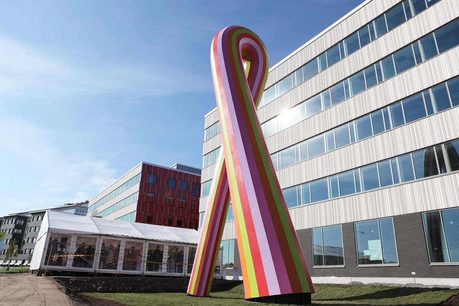 En färgglad skulptur i form av ett band framför en modern kontorsbyggnad.