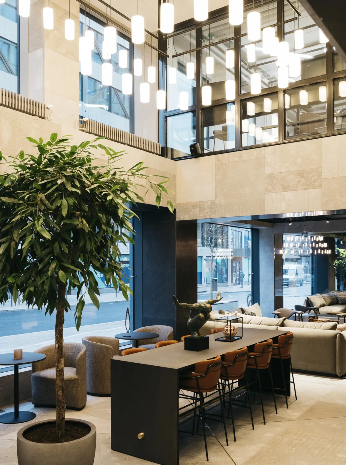2. En ljus lobby med stora fönster, gröna växter, soffor och bord.