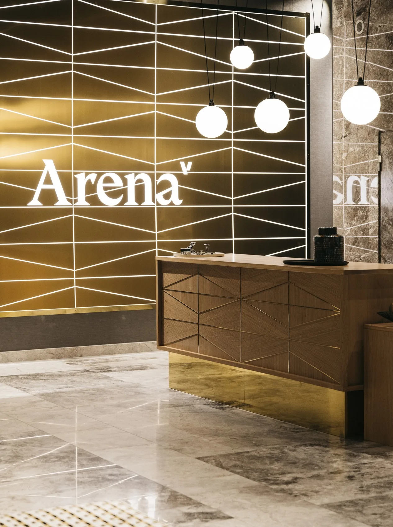 Reception med en trädisk framför en vägg prydd med texten "Arena" och geometriska mönster.