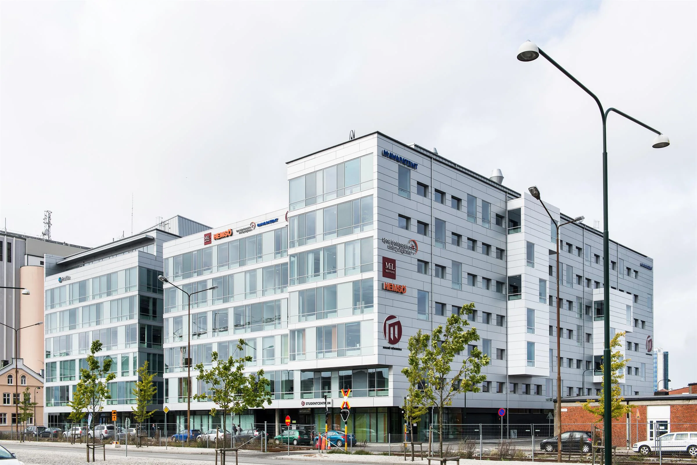 Flera sammanhängande kontorsbyggnader med glasfasad och butiksentréer på marknivå.