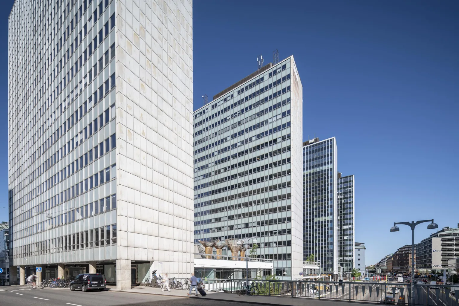 En arkitektonisk vy med flera höga, moderna kontorsbyggnader under en klarblå himmel.