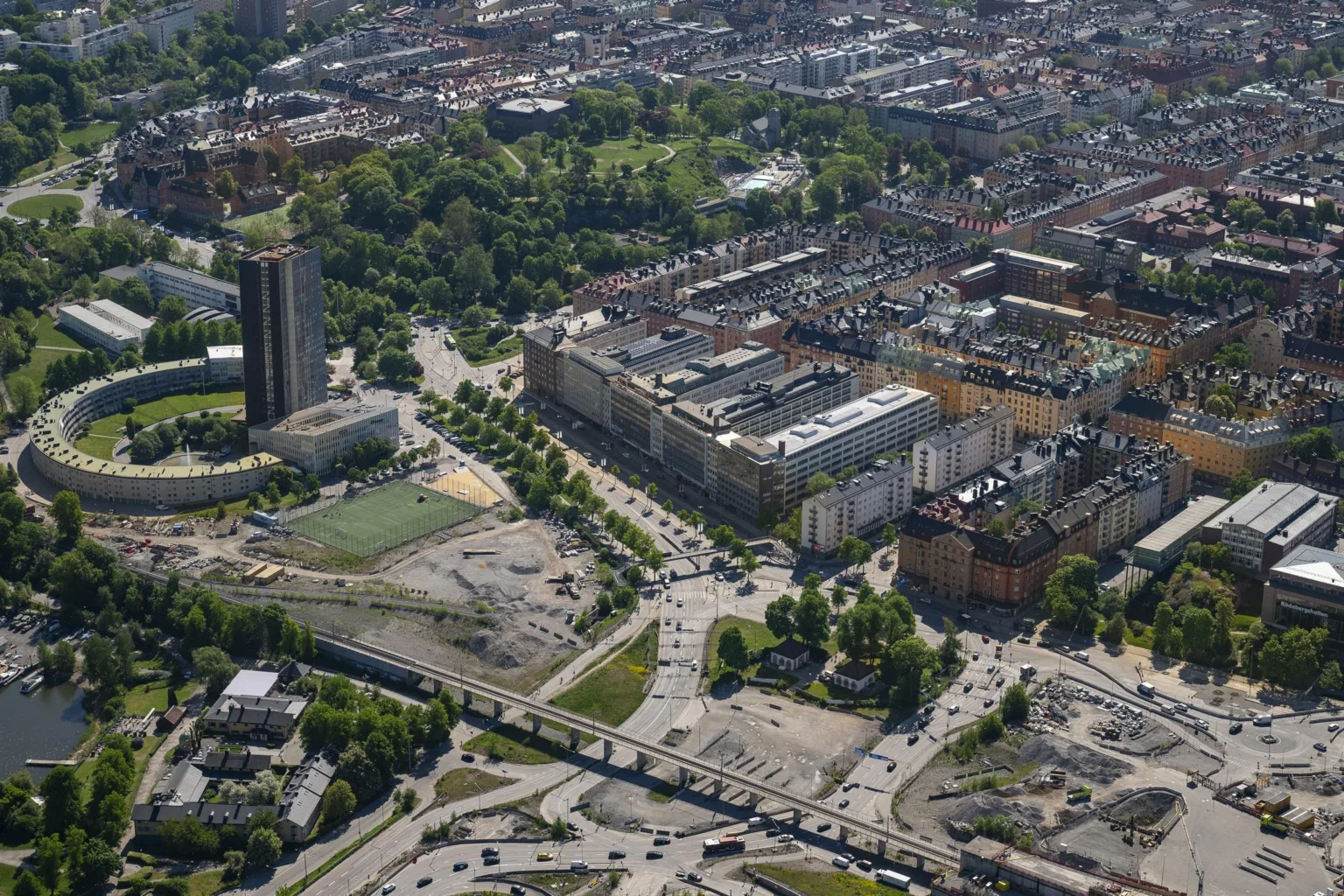 En flygbild över en stad med byggnader, vägar, parker och ett högt torn.