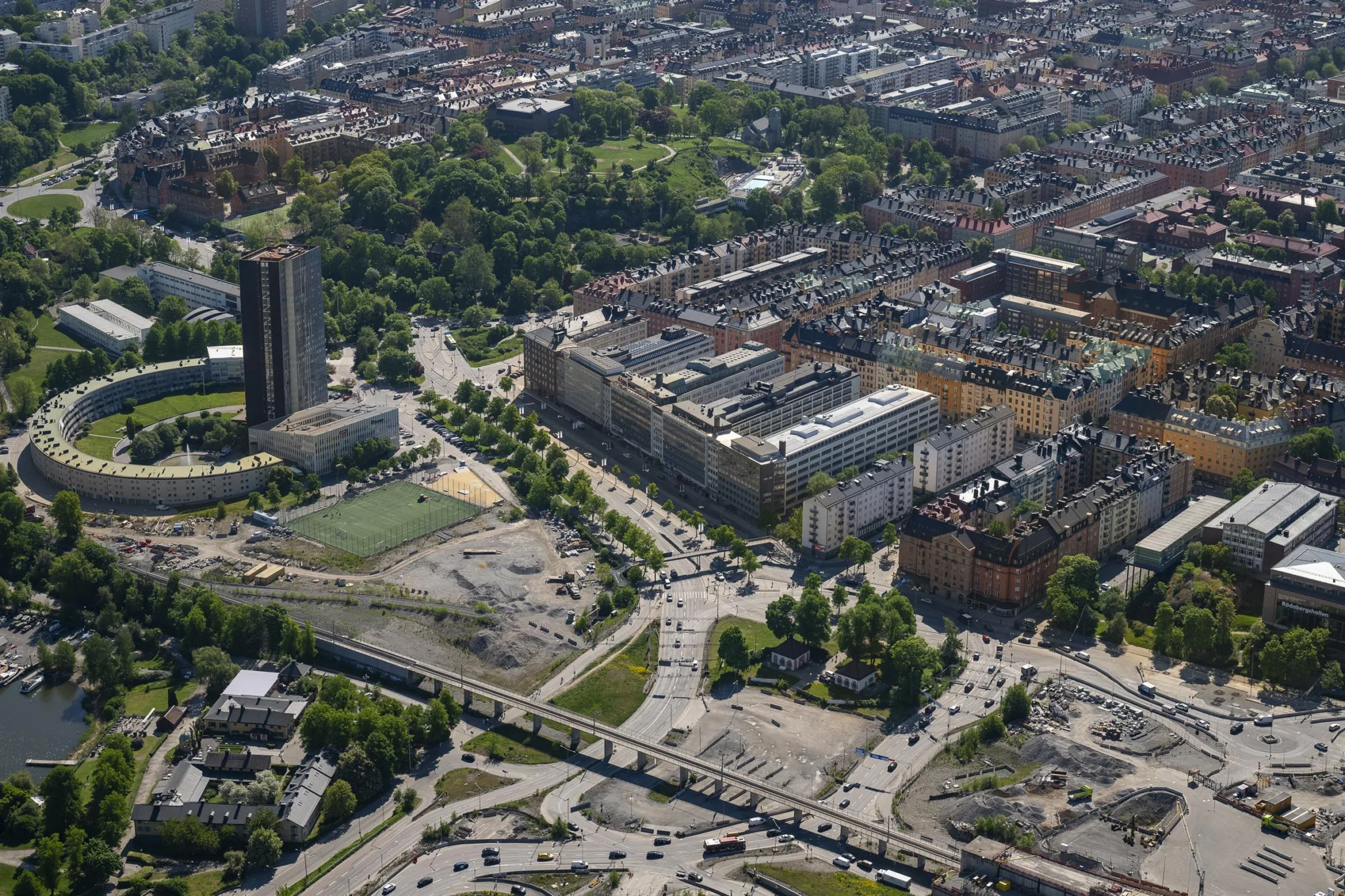 En flygbild över en stad med byggnader, vägar, parker och ett högt torn.