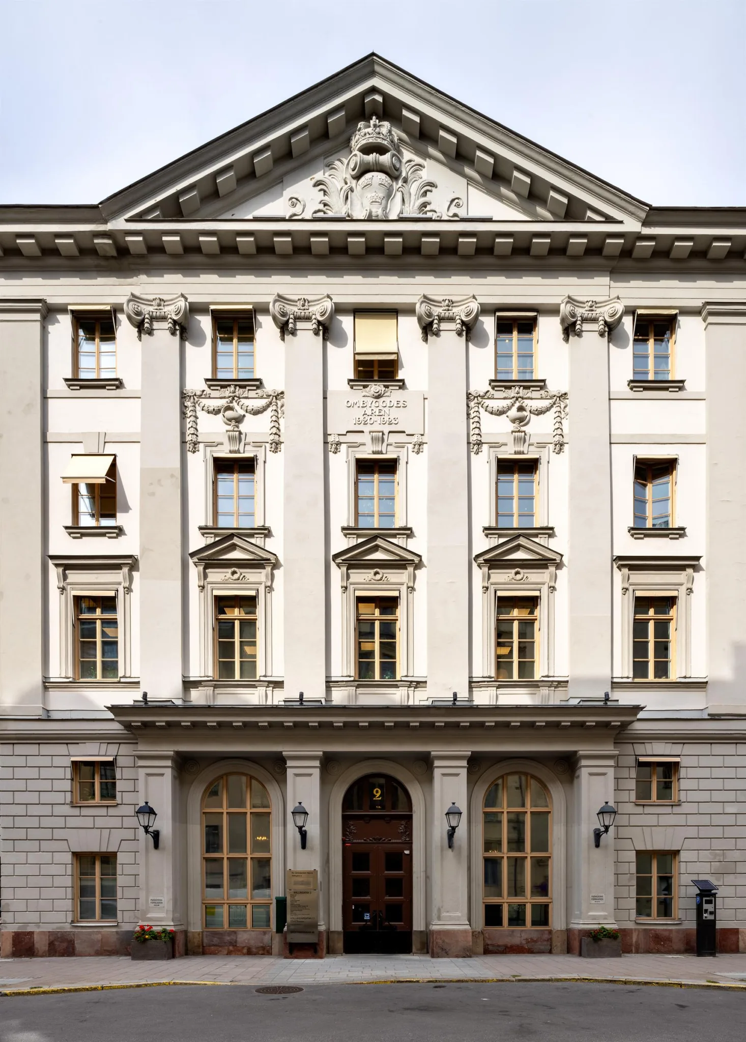 En vit byggnad med klassisk arkitektur, flera fönster och en välvd entré med dekorativa detaljer.