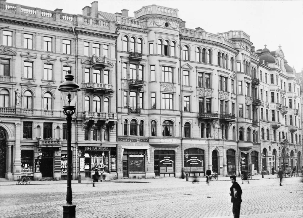 En svartvit bild av en äldre byggnad med flera våningar och butiker på bottenvåningen.