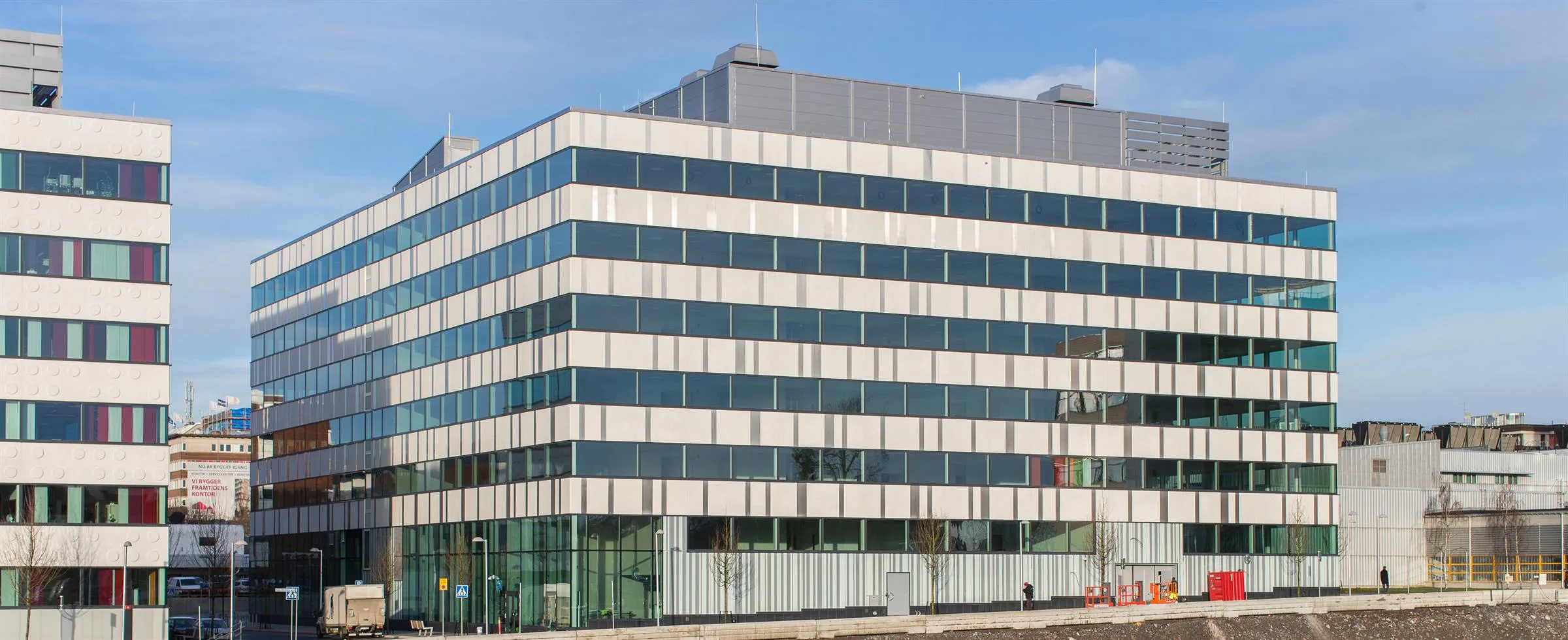 5. En fyrkantig byggnad med glasfasad och tak med tekniska installationer, fotograferad mot en blå himmel.