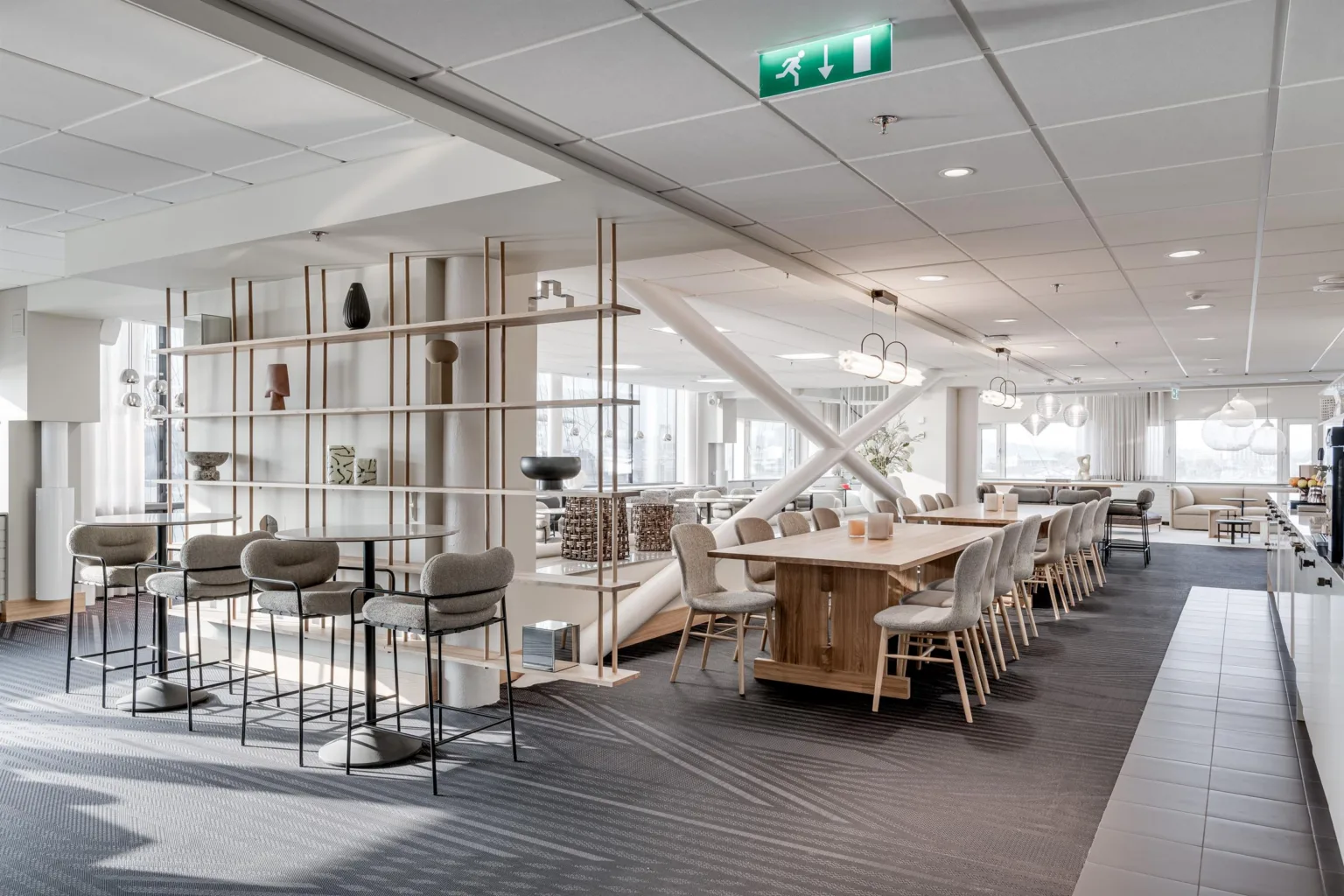 En modern kontorsmiljö med bord, stolar och hyllor i ljusa färger.