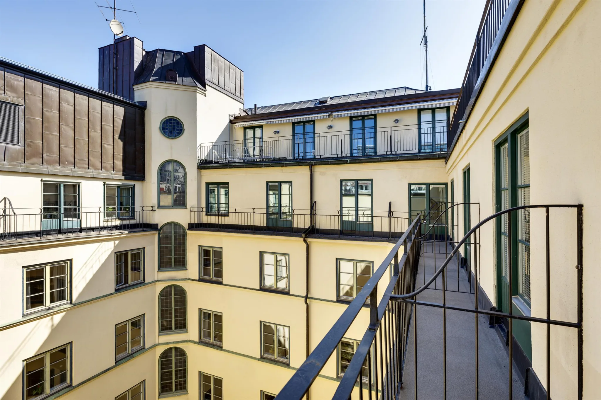 En innegård med en balkong och utsikt över fasader med stora fönster och klassisk arkitektur.