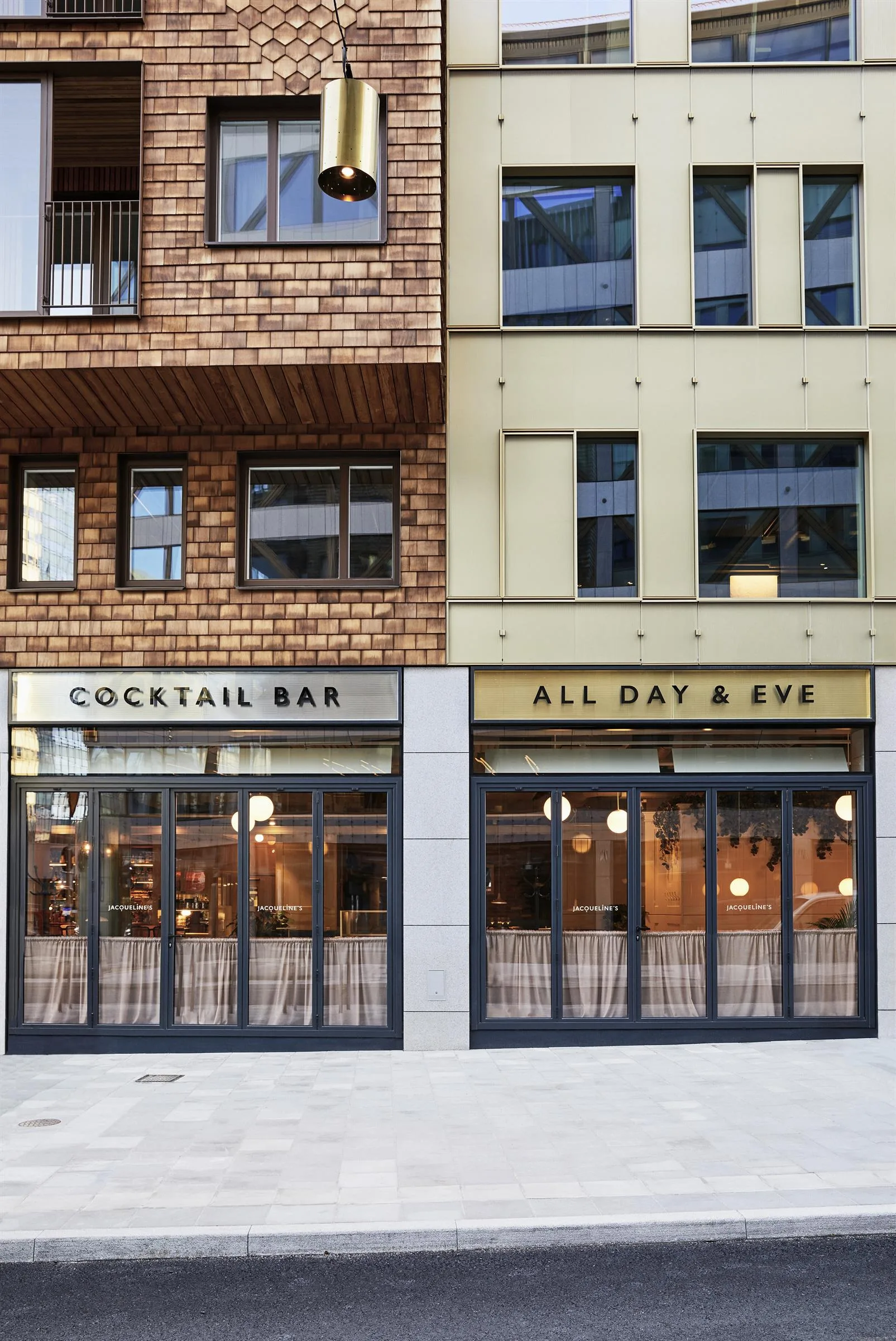 Två restaurangfasader bredvid varandra med skyltarna "Cocktail Bar" och "All Day & Eye" ovanför glasdörrar.