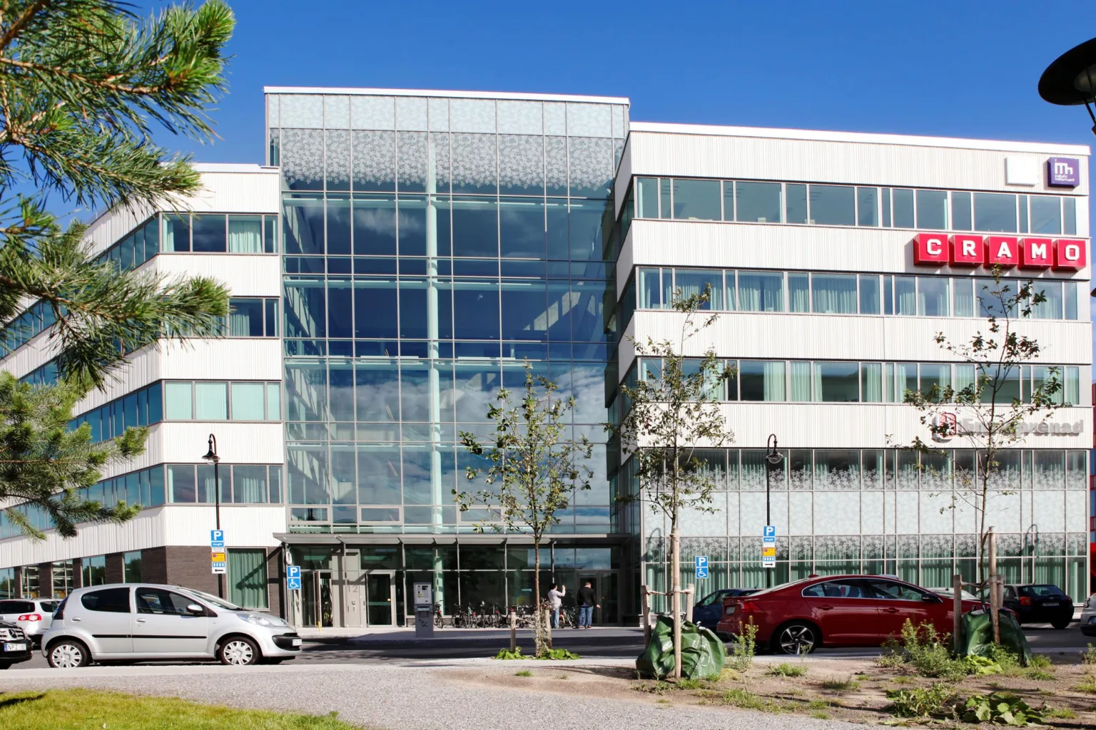 4. En modern kontorsbyggnad med glasfasad och parkerade bilar framför.