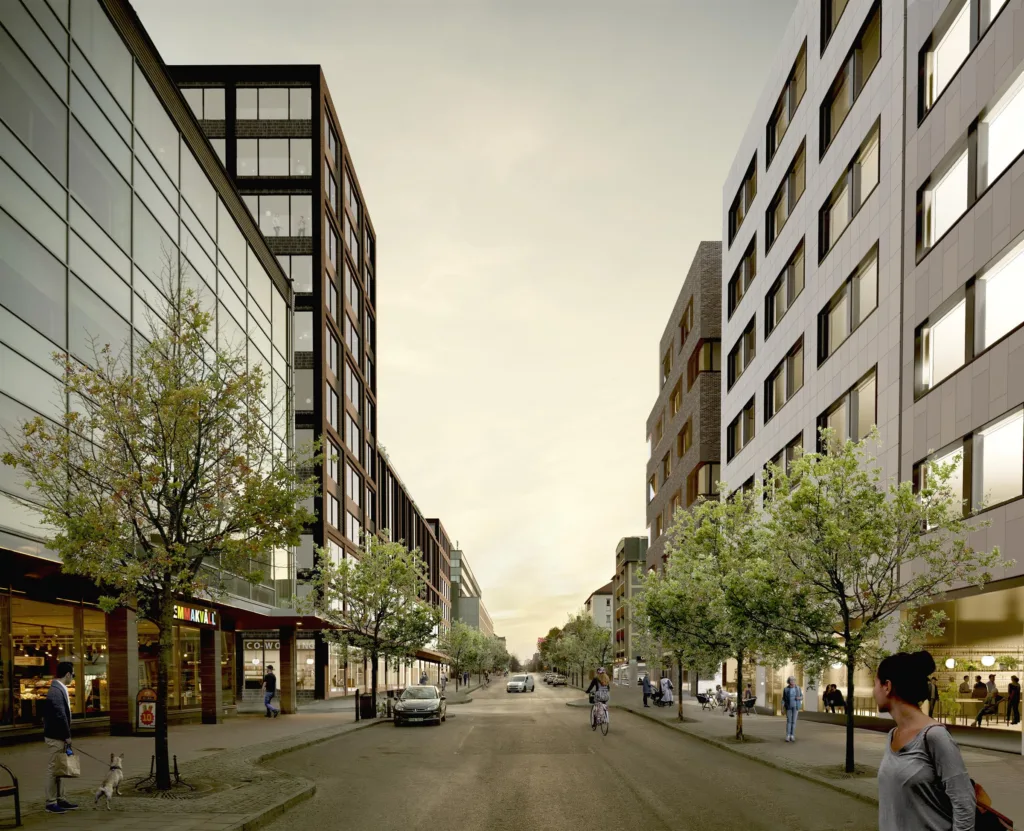 - En stadsgata kantad av moderna byggnader med glasfasader och träd, med människor och bilar på vägen.