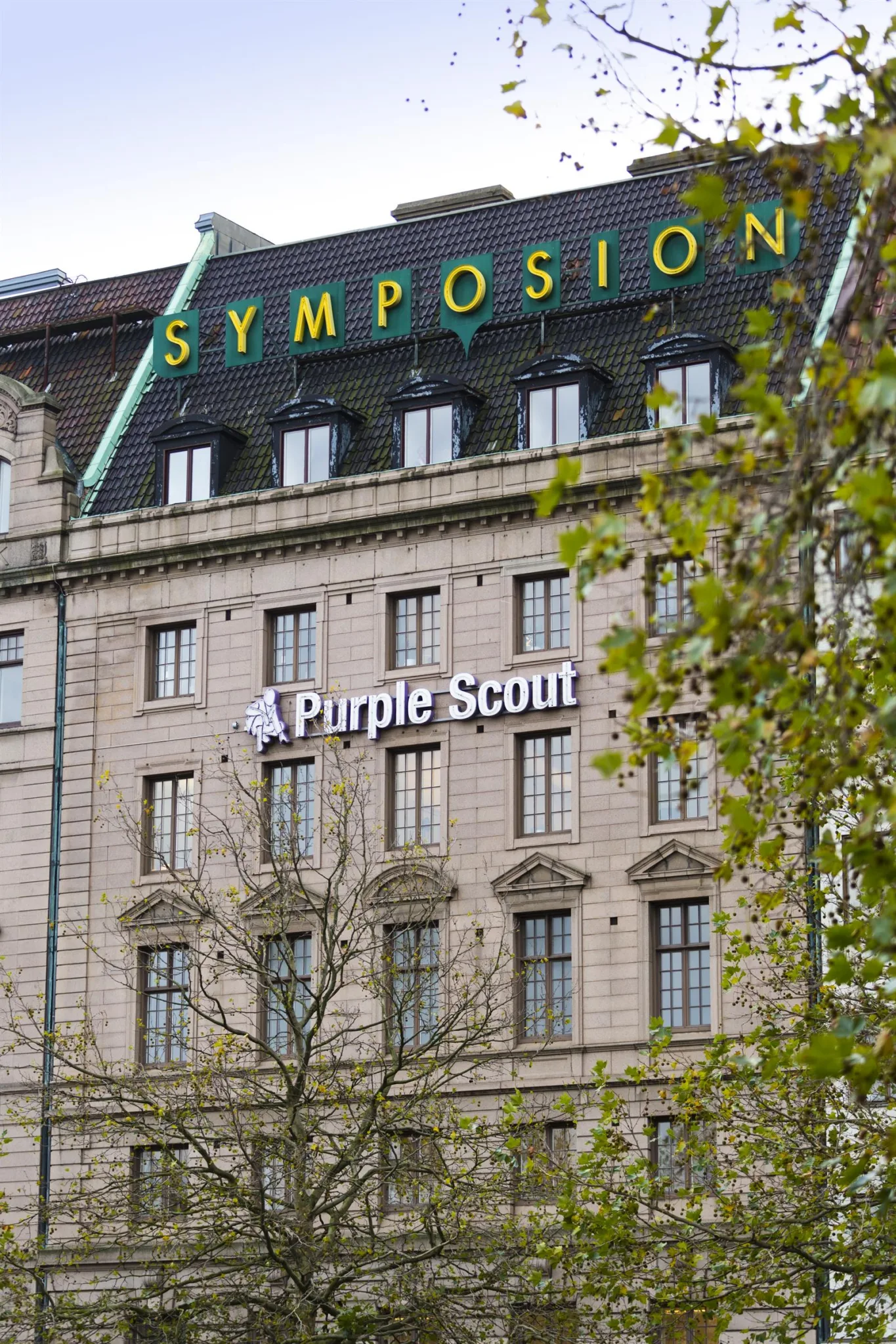 2. En byggnad med texten "Purple Scout" och "Symposion" på fasaden.