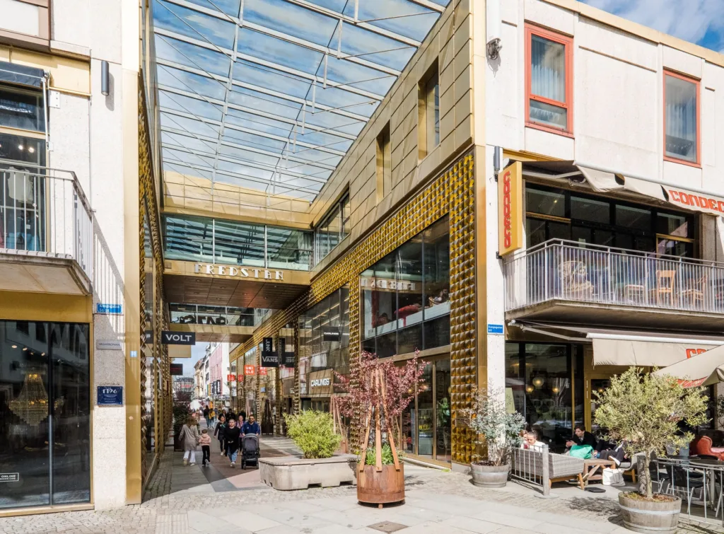 Ett modernt köpcentrum med glasöverbyggnad och butiker på båda sidor.