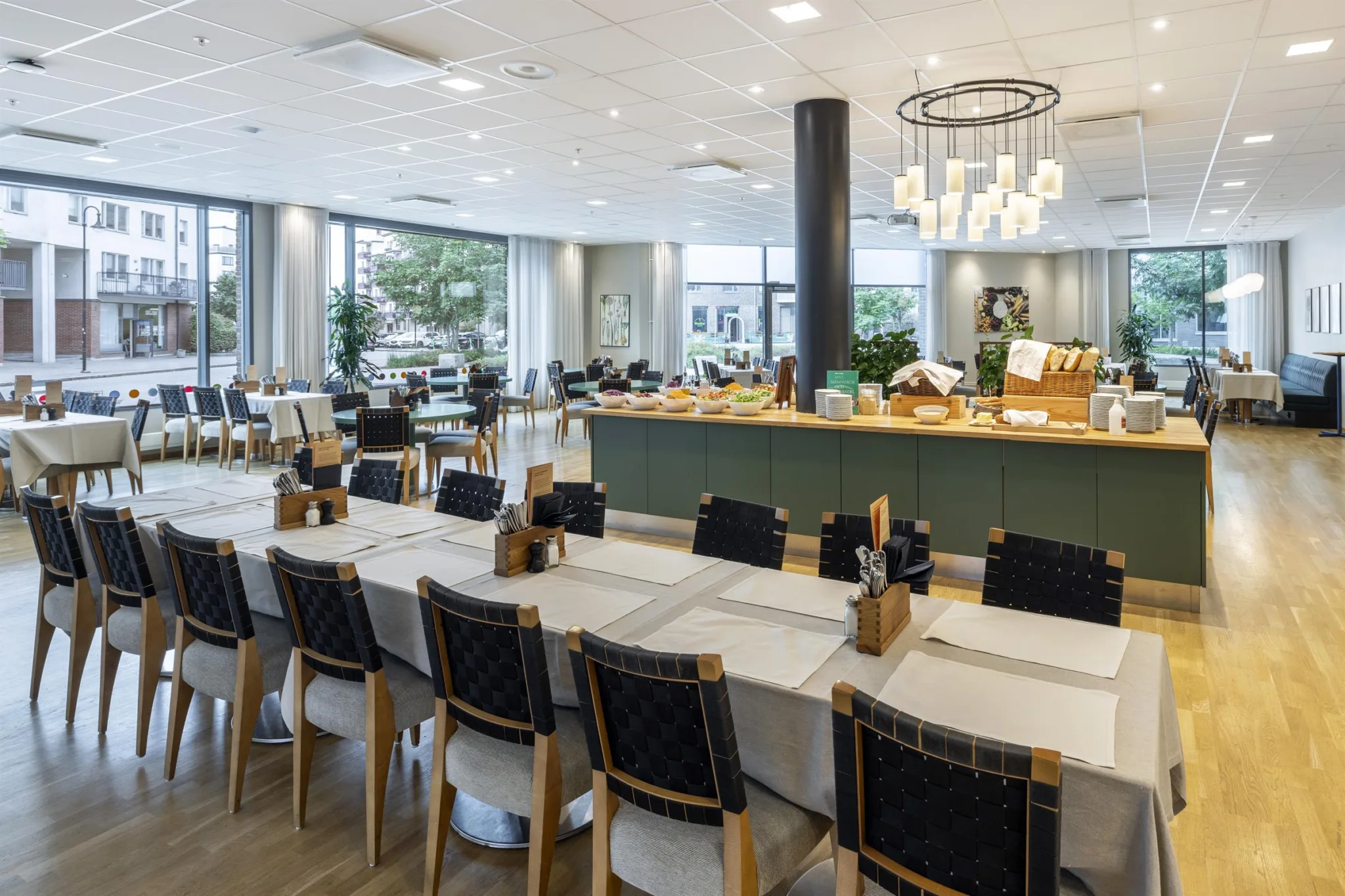 2. En matsal med långbord, svarta stolar och en buffé med mat i bakgrunden.