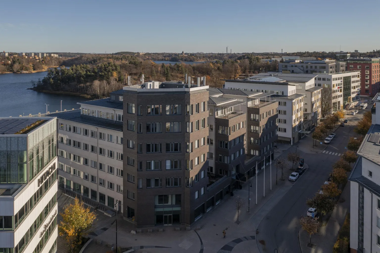 En stor byggnad med modern arkitektur, omgiven av en väg och natur i bakgrunden.