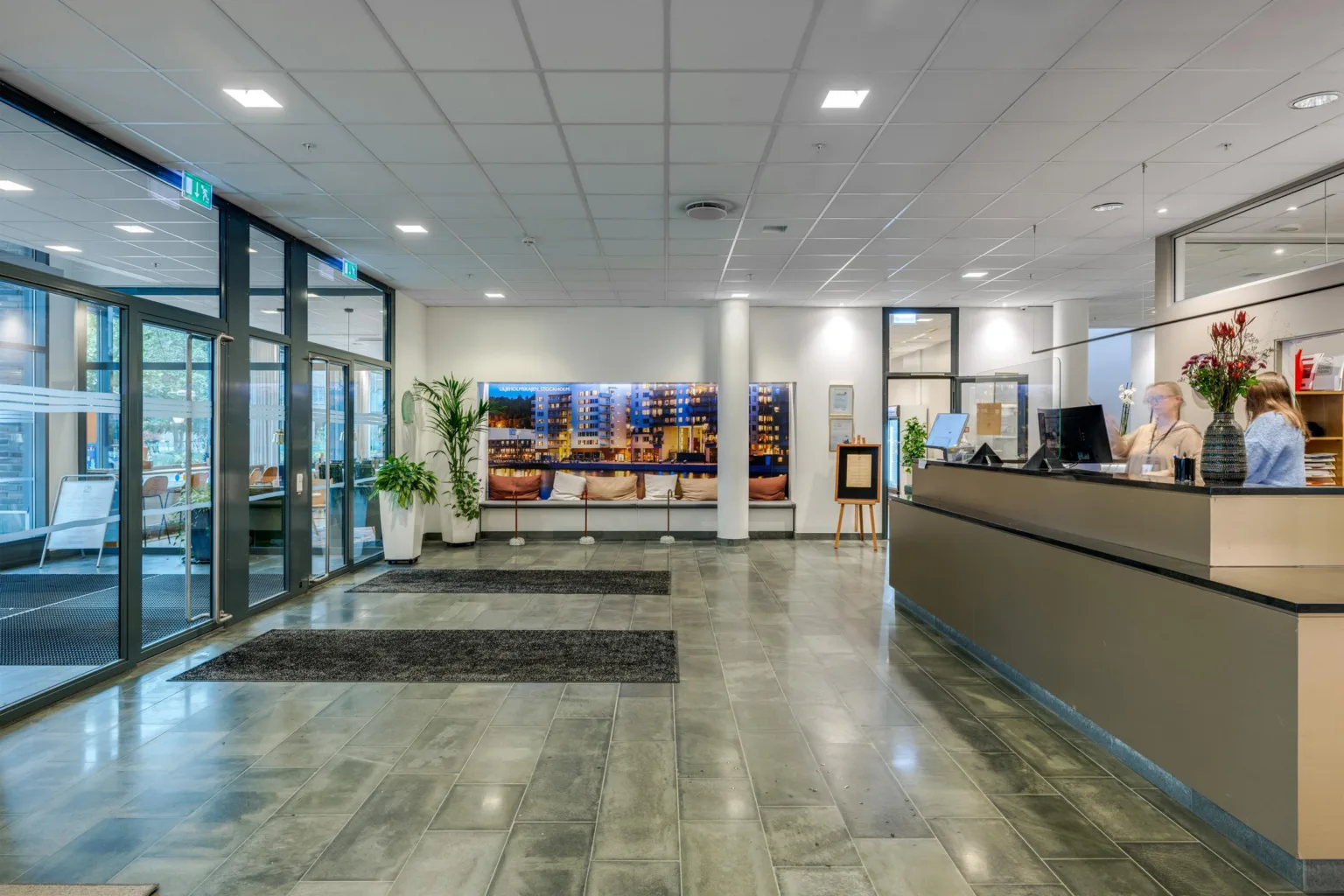 4. En reception med en lång disk, väggdekorationer och glasdörrar som leder ut.