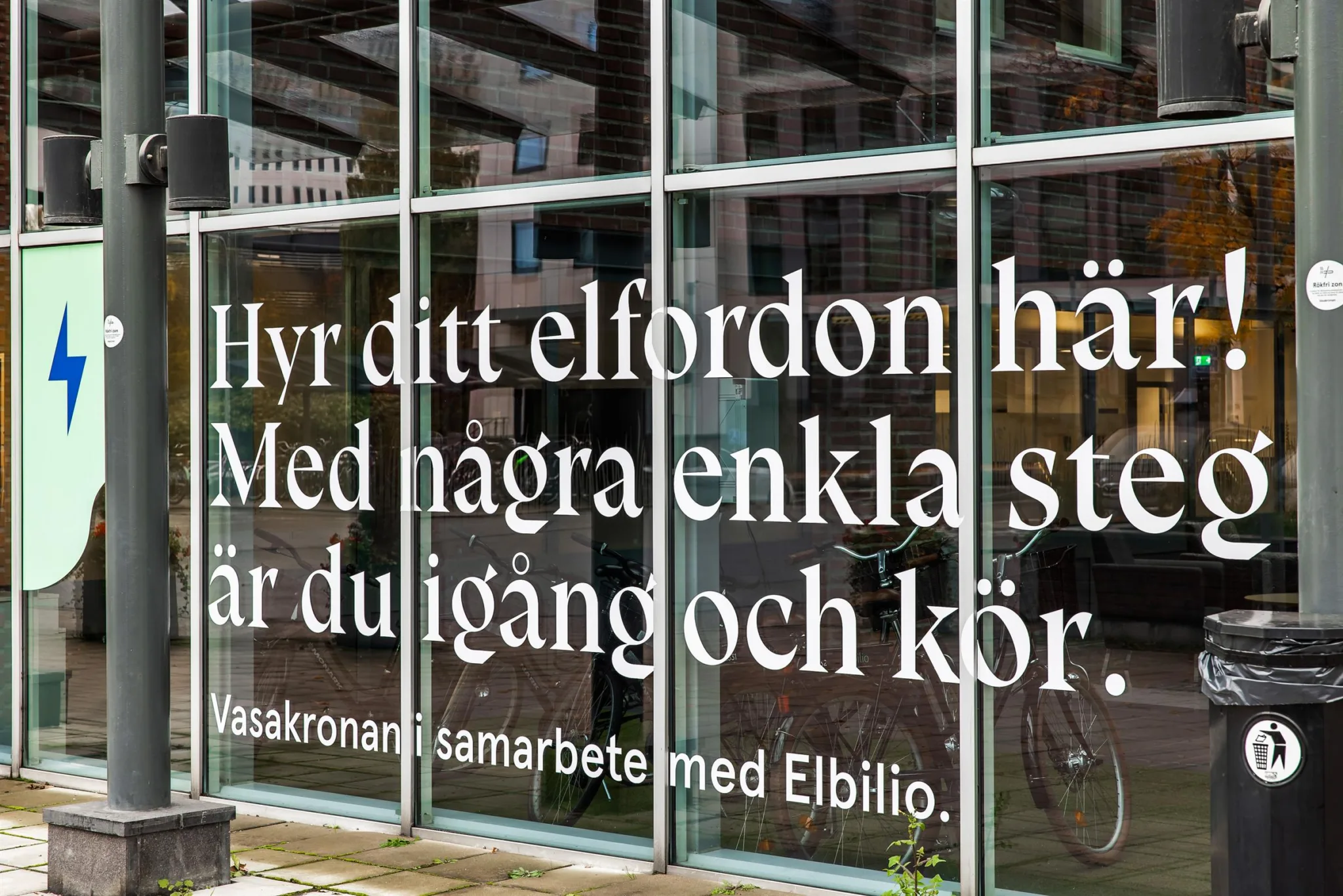 Text på glasruta: "Hyr ditt elfordon här. Med några enkla steg är du igång och kör. I samarbete med Elbilio."