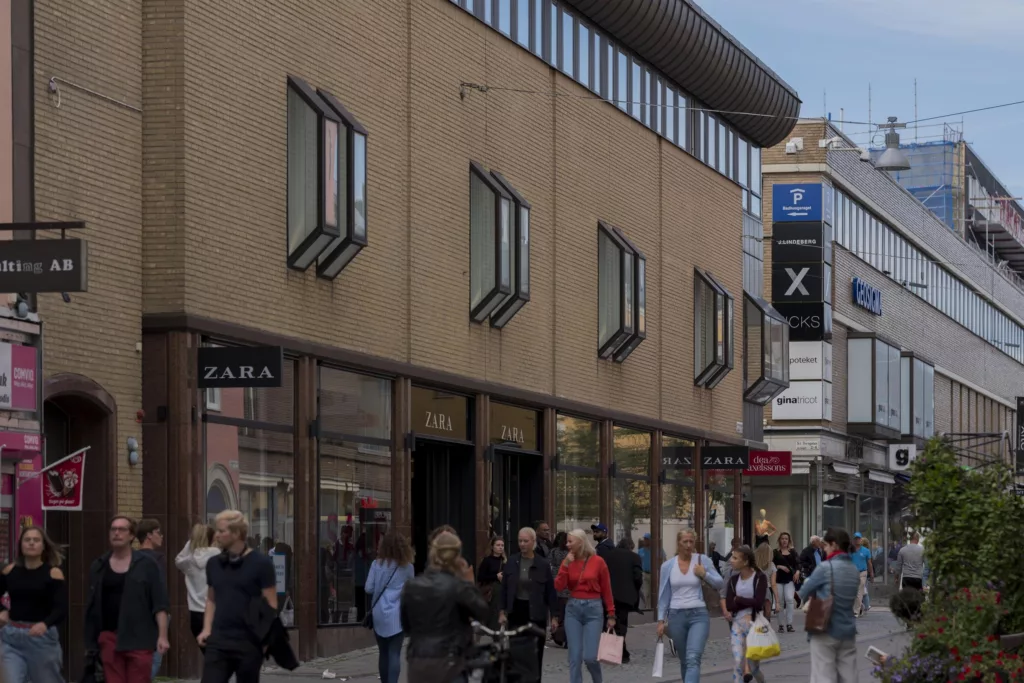 3. En byggnad med flera butiker, inklusive Zara, och människor som går på trottoaren.