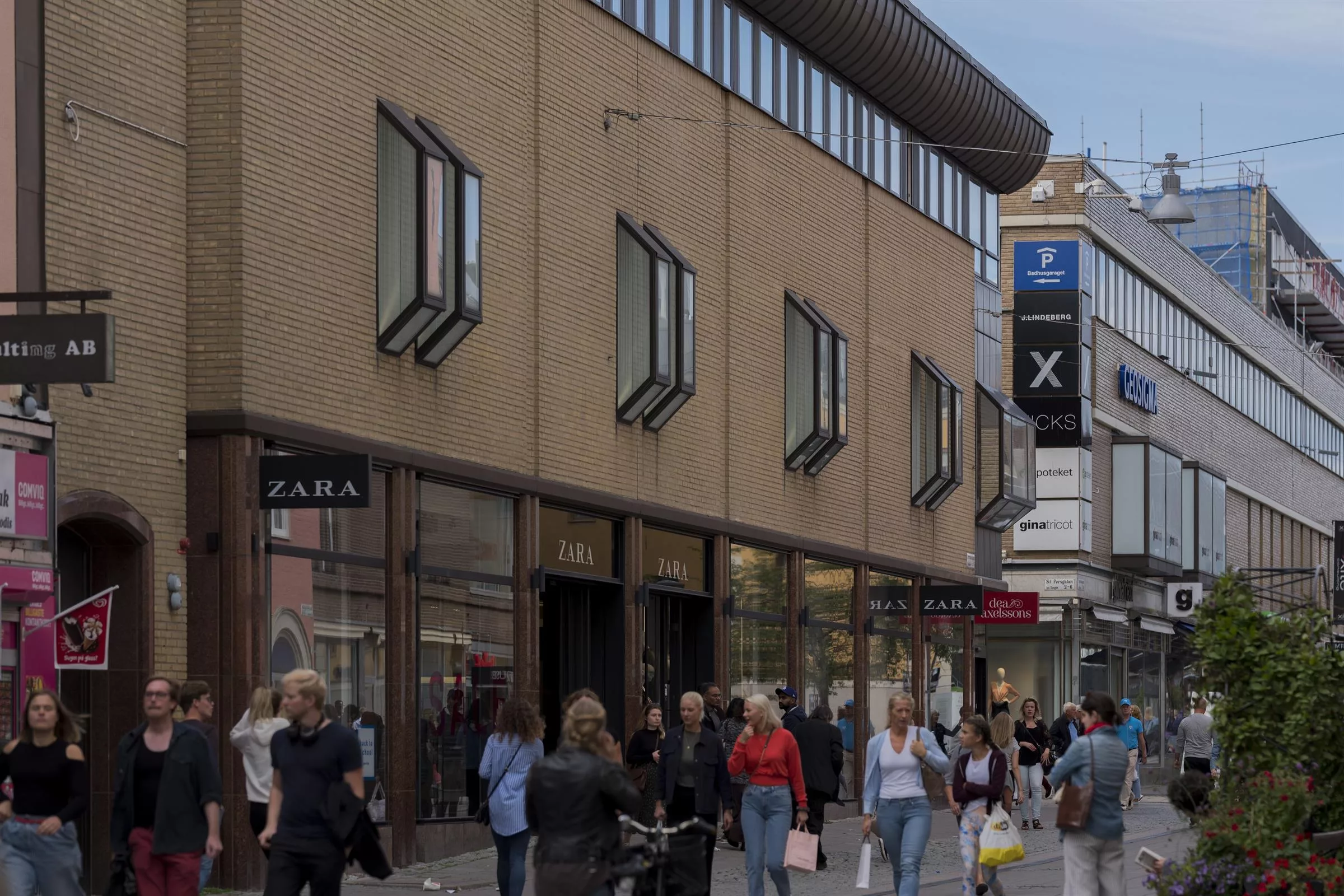 3. En byggnad med flera butiker, inklusive Zara, och människor som går på trottoaren.