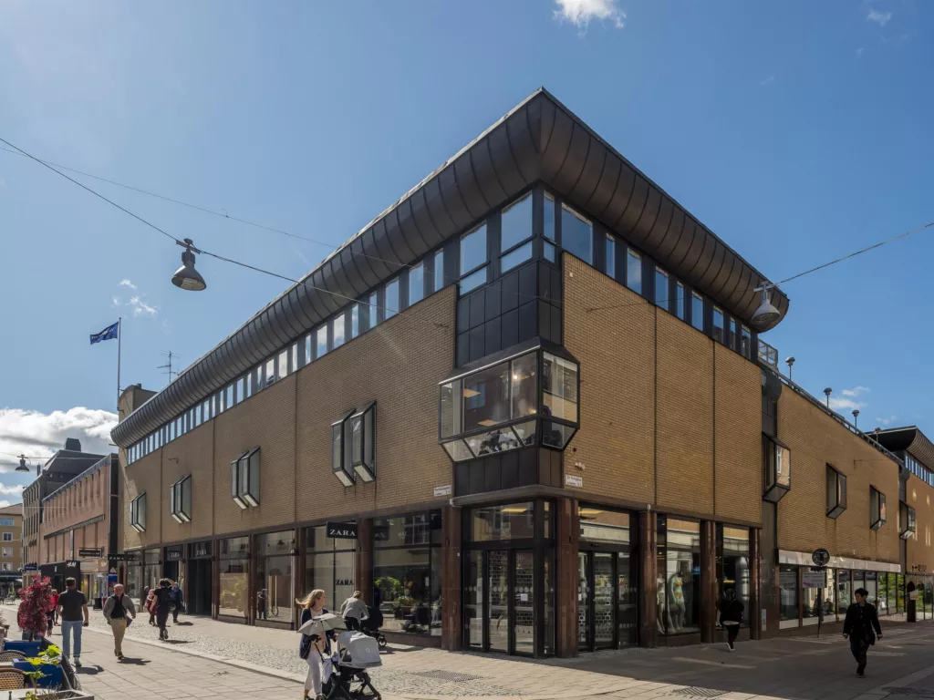 4. En modern byggnad med stora fönster, människor och cyklar vid trottoaren.