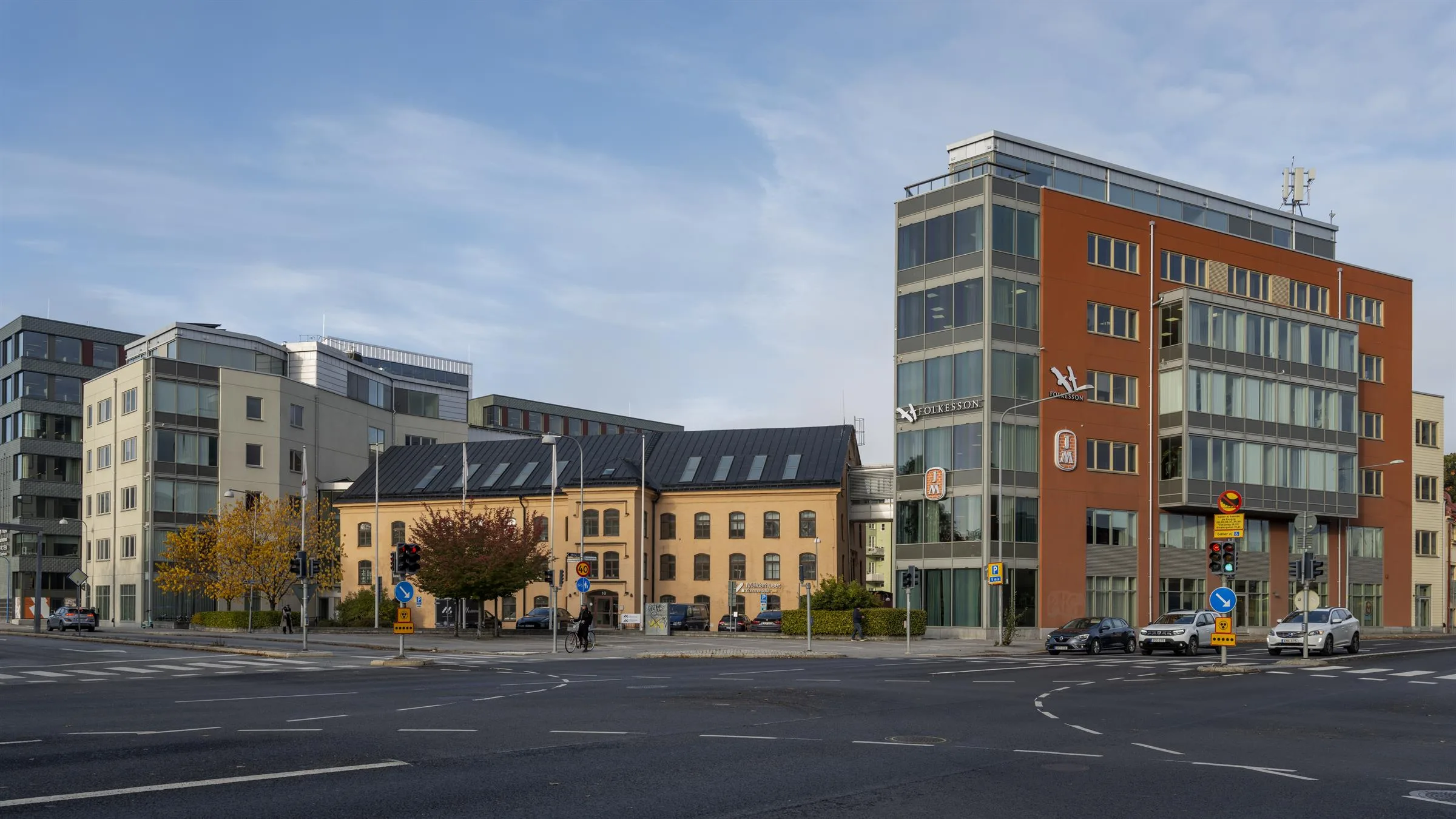 3. Ett område med en blandning av äldre och moderna byggnader, där en röd byggnad står bredvid en glasfasad.
