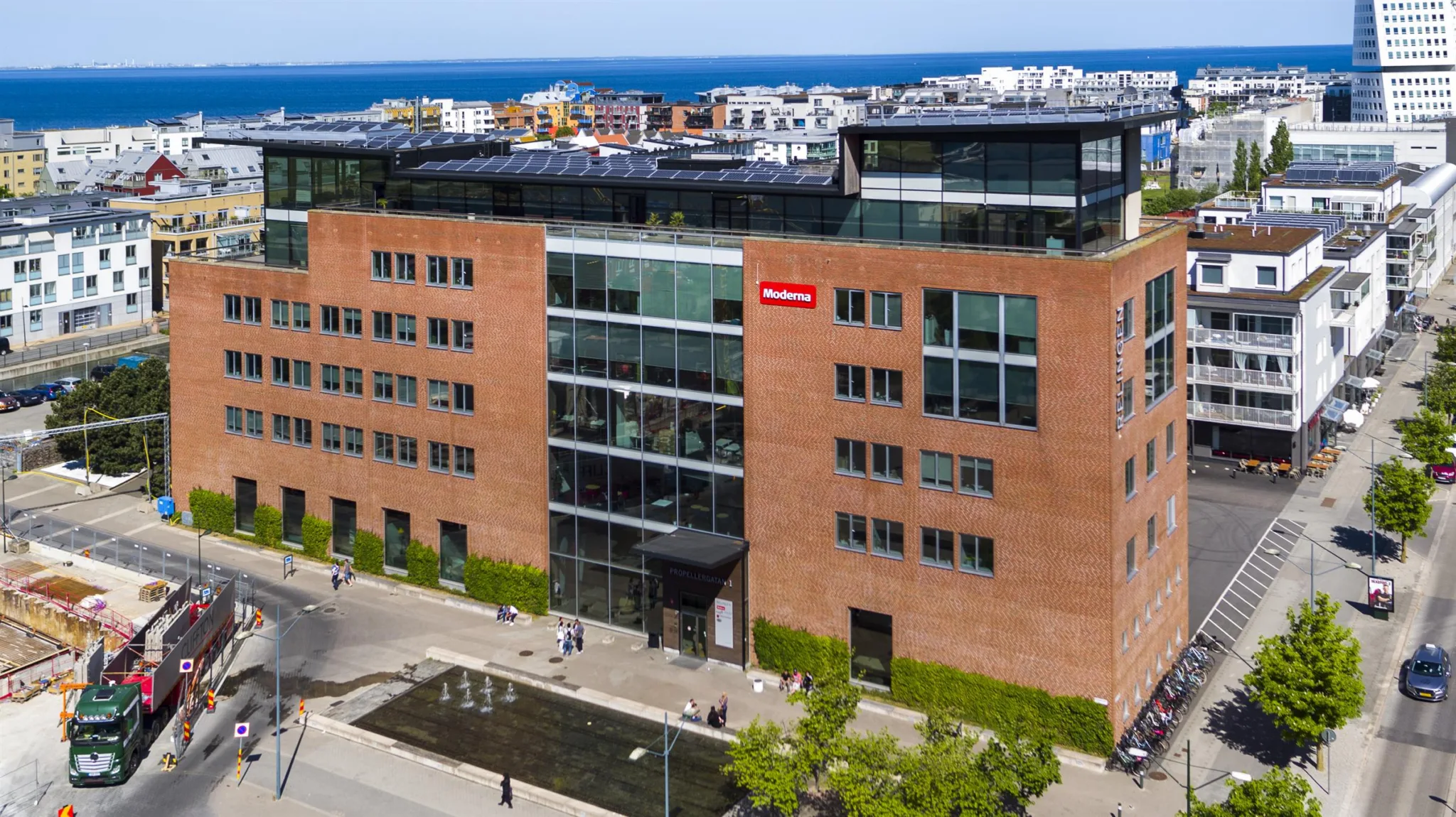 2. Modern tegelbyggnad med stora glaspartier, ett rött skylt med texten "Skanska" synligt på fasaden.