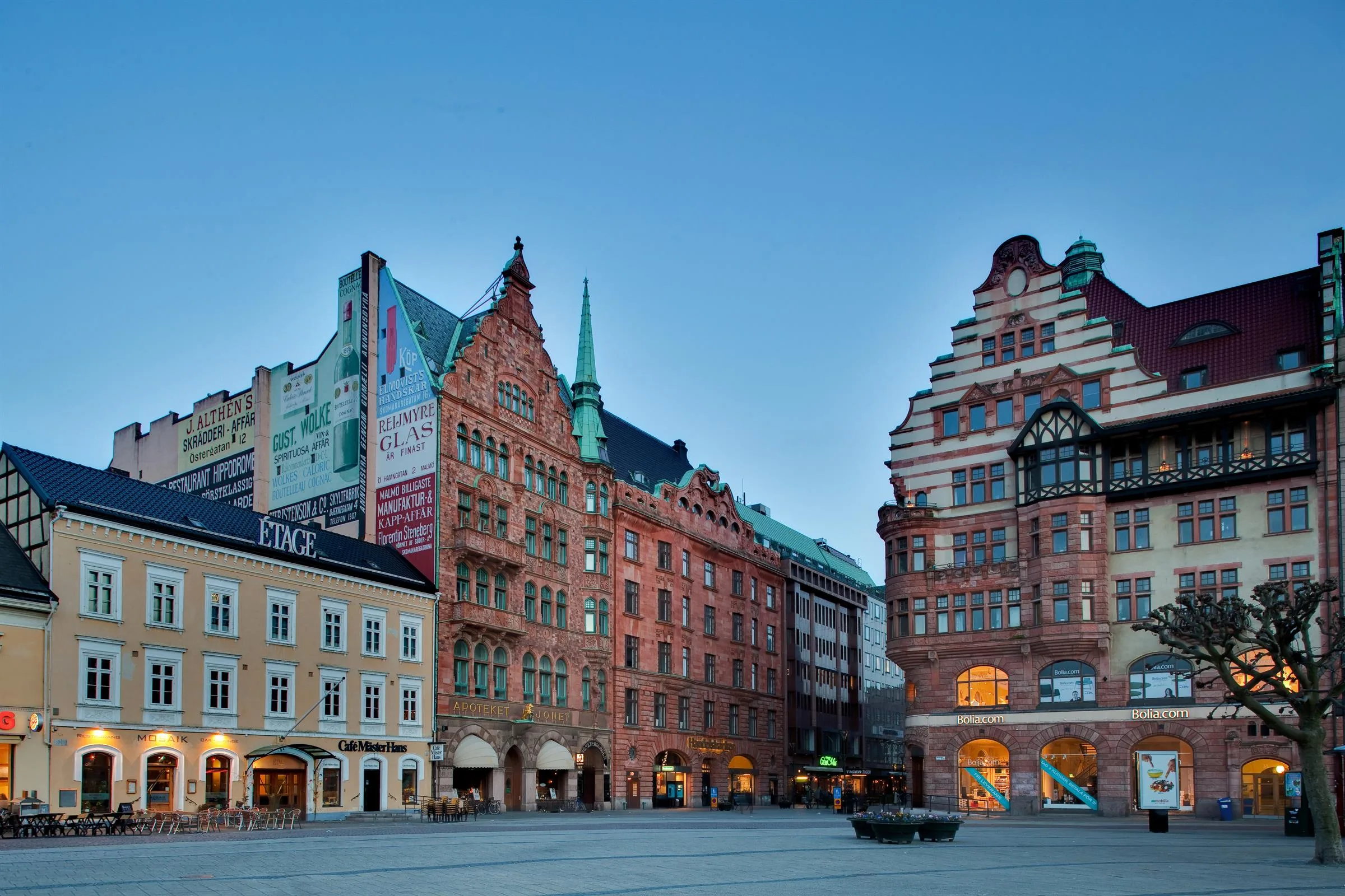 Ett torg med flera färgglada och historiska byggnader, en öppen plats med blå himmel.
