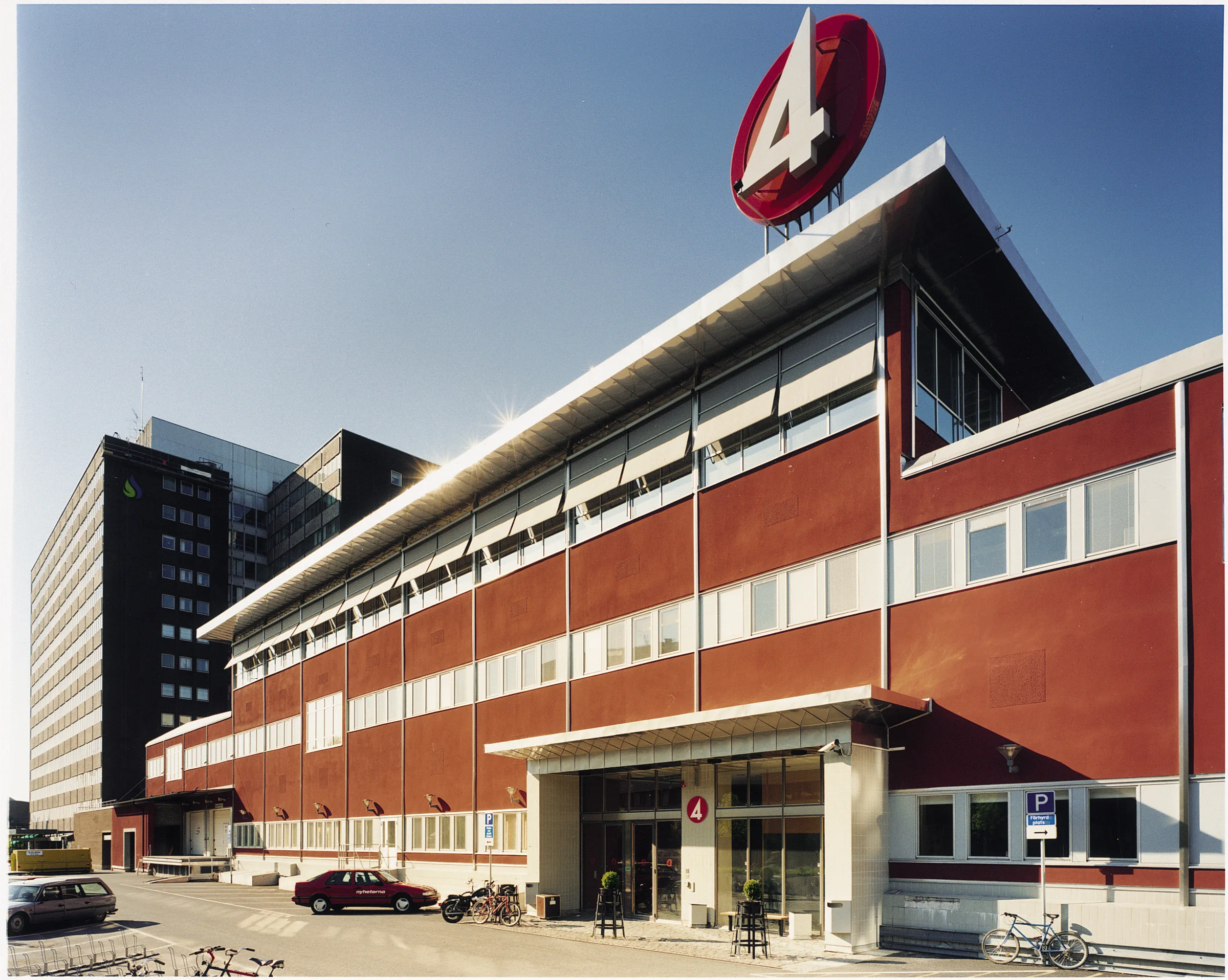 1. En byggnad med tegelväggar och en stor "4"-skylt på taket, omgiven av parkeringsplatser.