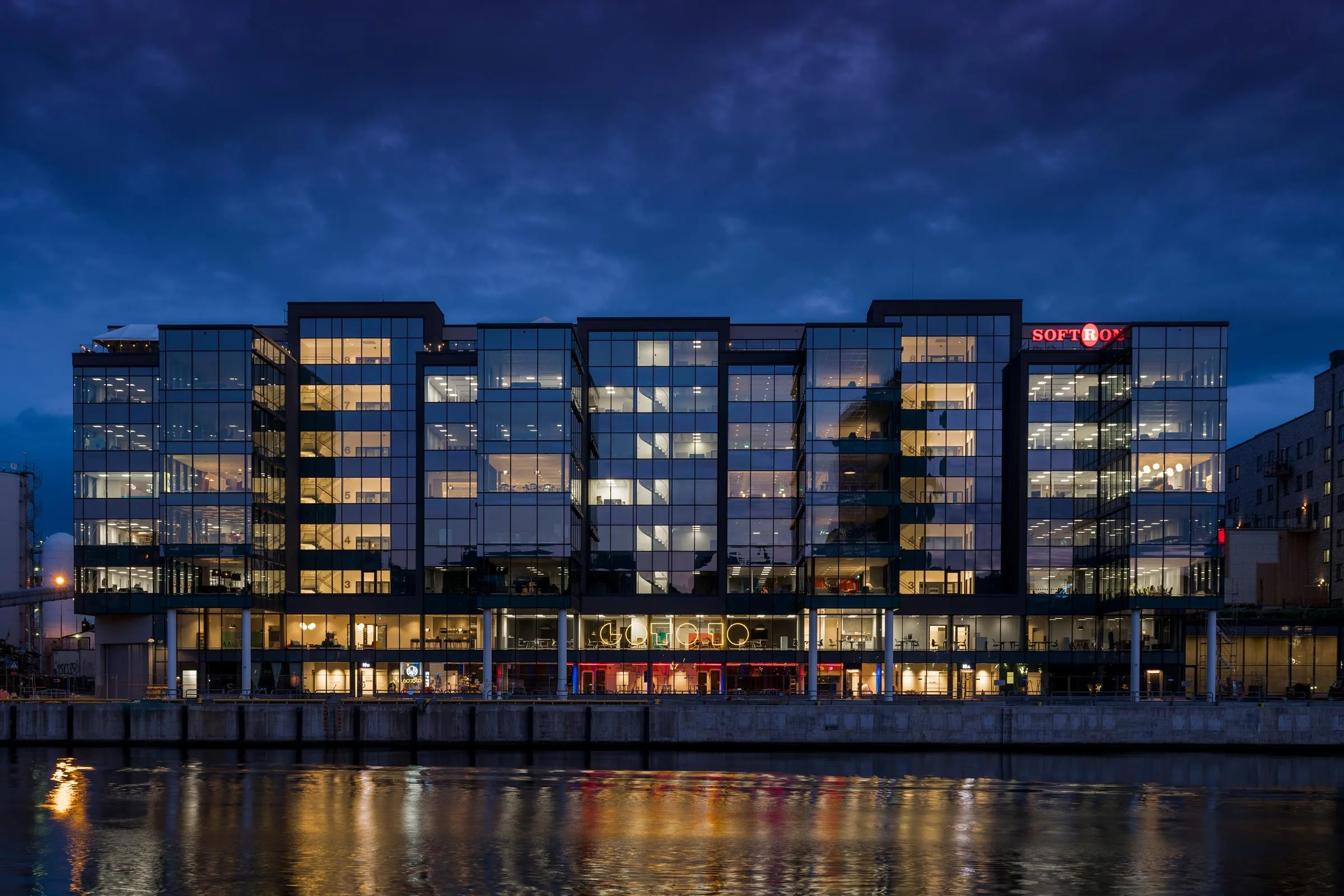 2. En modern byggnad med glasfasader vid vattnet, belyst på kvällen.