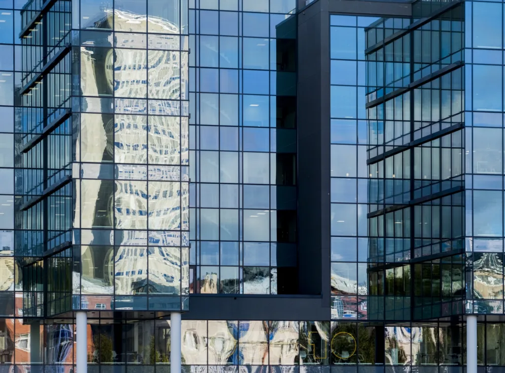 1. Glasfasader med reflektioner av en annan byggnad och omgivningen.