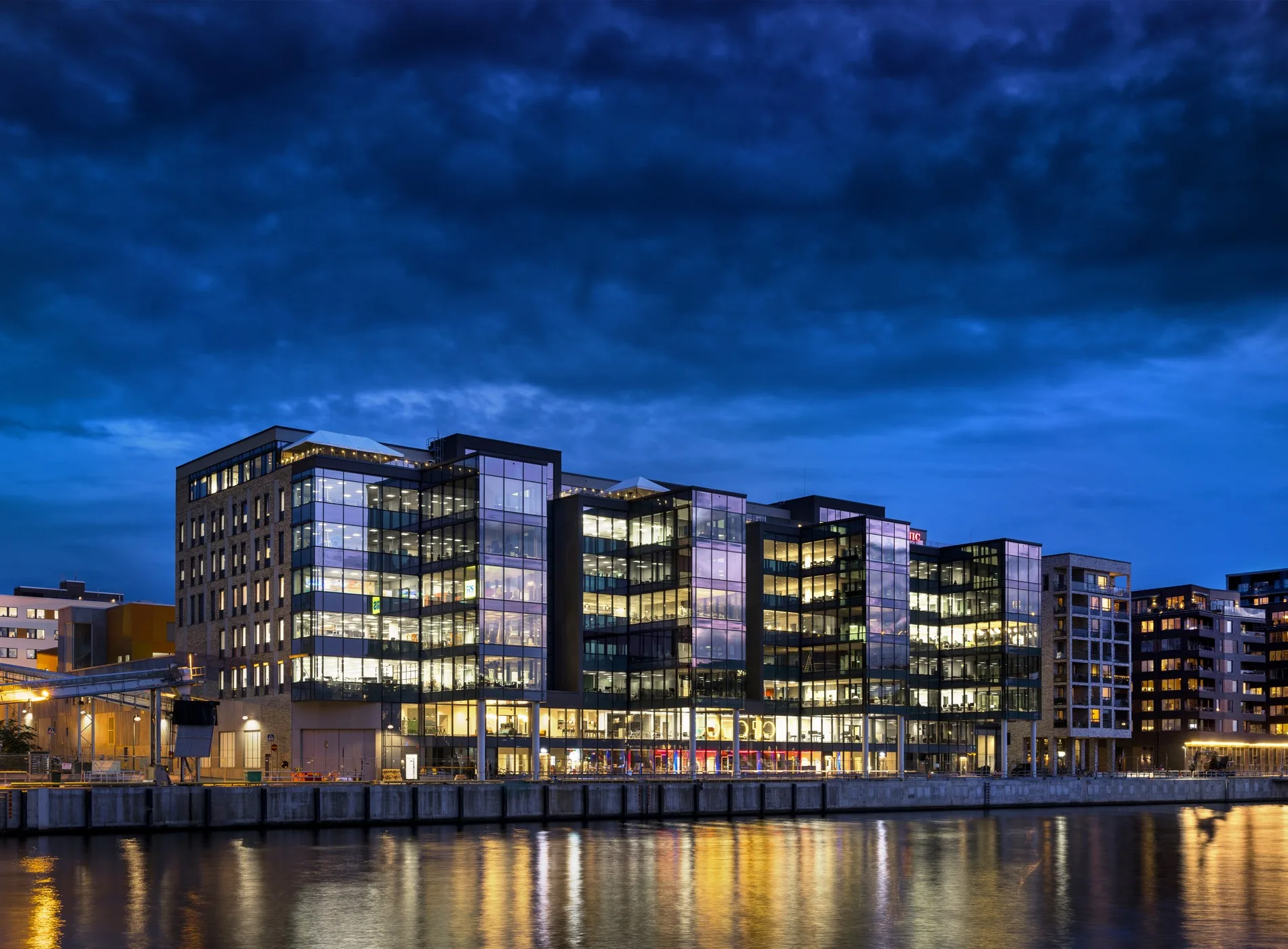 3. Flera moderna byggnader med glasfasader vid vattnet under kvällsbelysning.
