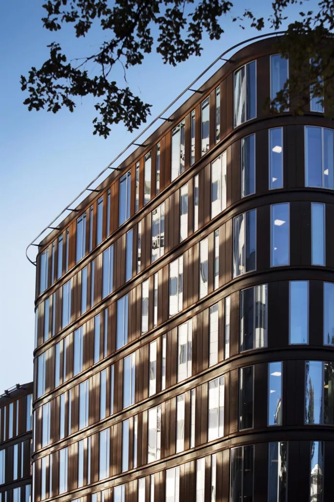 2. En modern byggnad med glas- och träfasad, belyst av starkt solljus med en klar himmel.