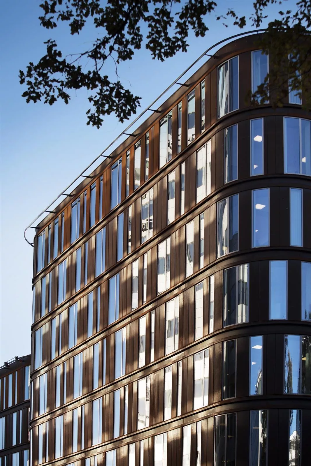 2. En modern byggnad med glas- och träfasad, belyst av starkt solljus med en klar himmel.