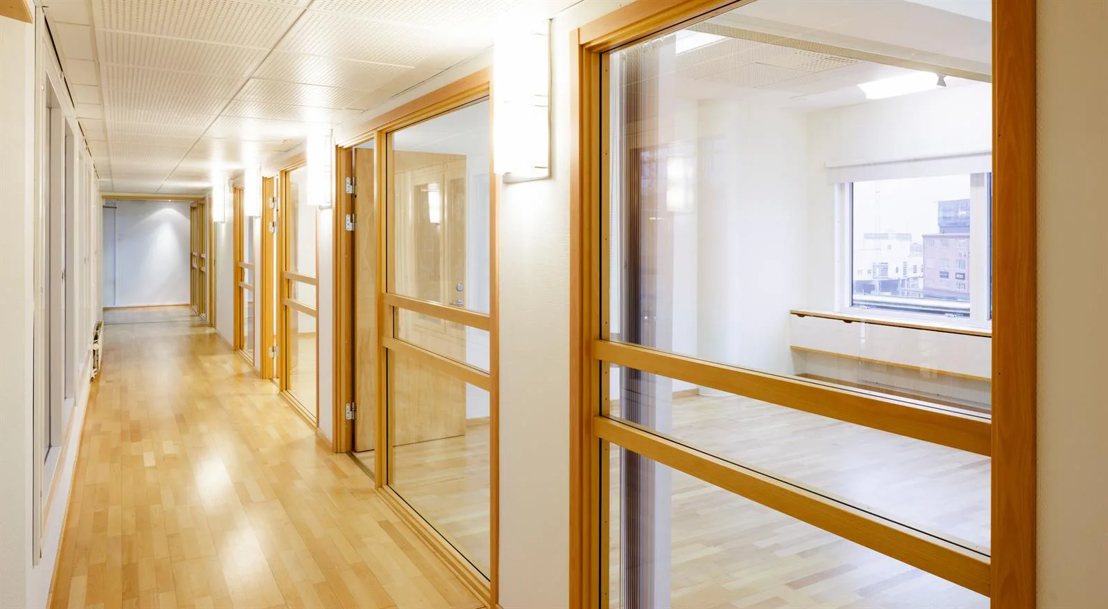 1. En ljus korridor med stora glaspartier och träramar längs väggarna.