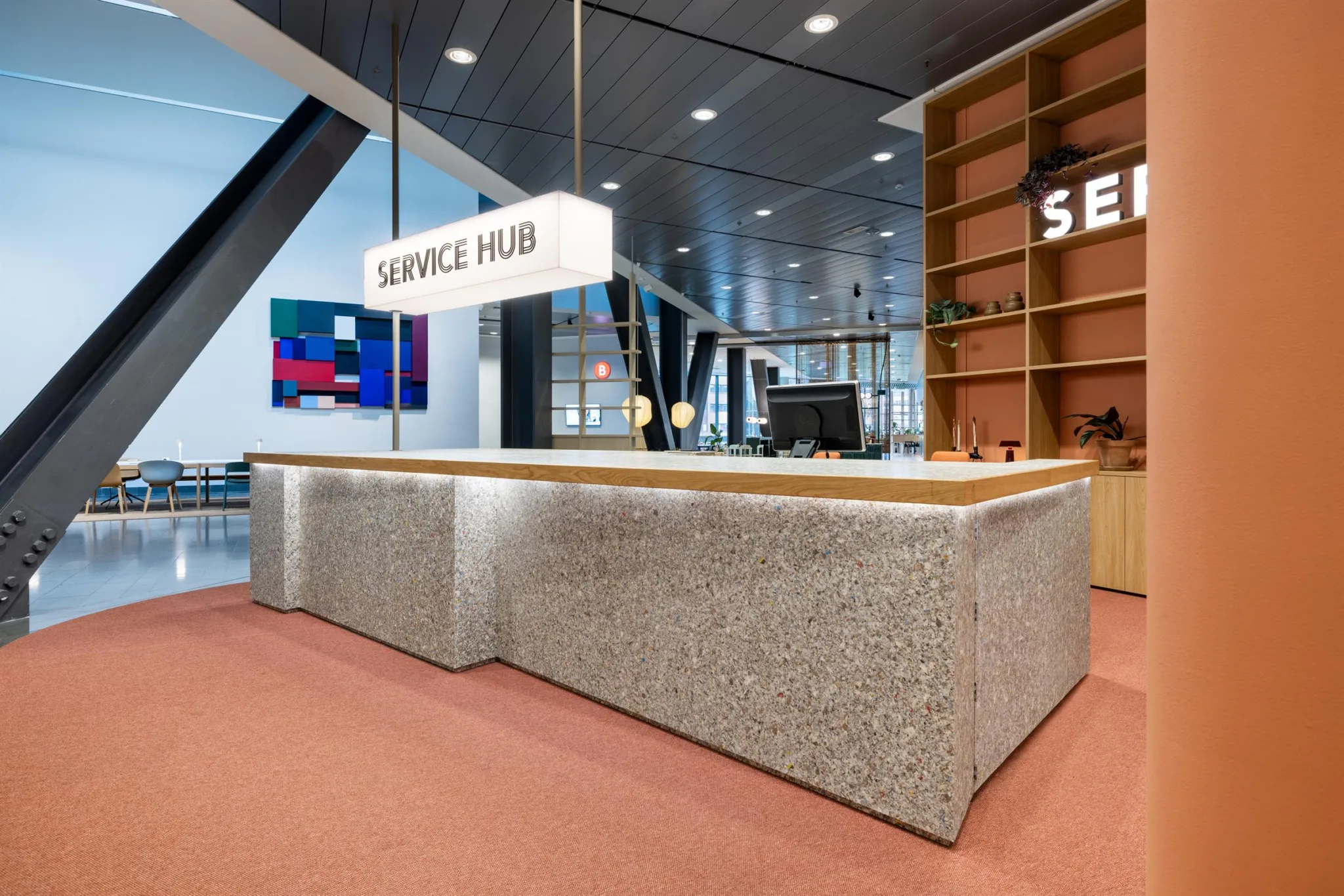 En receptionsdisk märkt med skylten "Service Hub", med bokhyllor och dekorationer i bakgrunden.